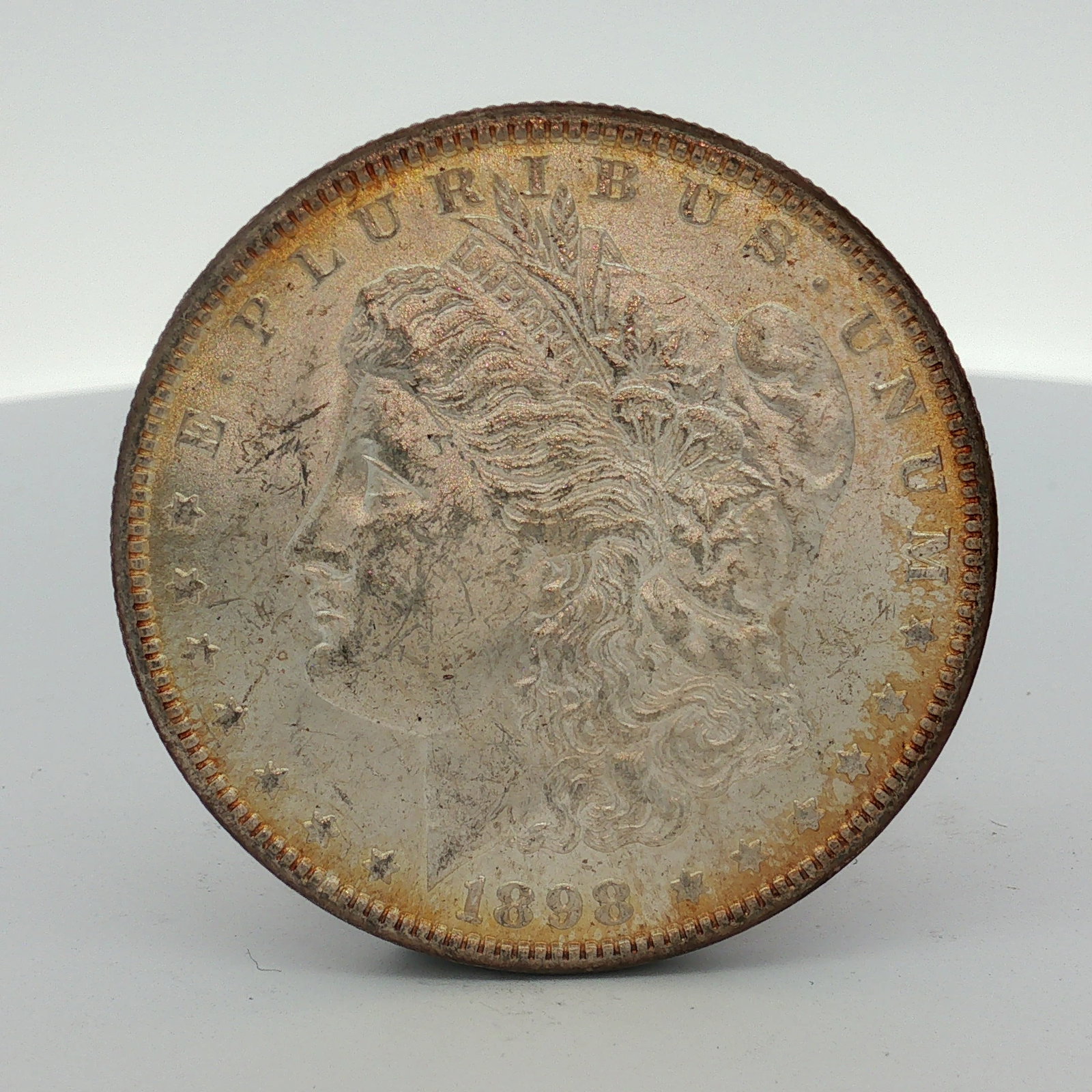 1898-O US Morgan Silver Dollar Coin Circulated: This 1898-O US Morgan silver dollar was struck at the New Orleans Mint. The coin features the Liberty Head obverse and the Heraldic Eagle reverse. It is composed of 0.900 fine silver. The obverse disp