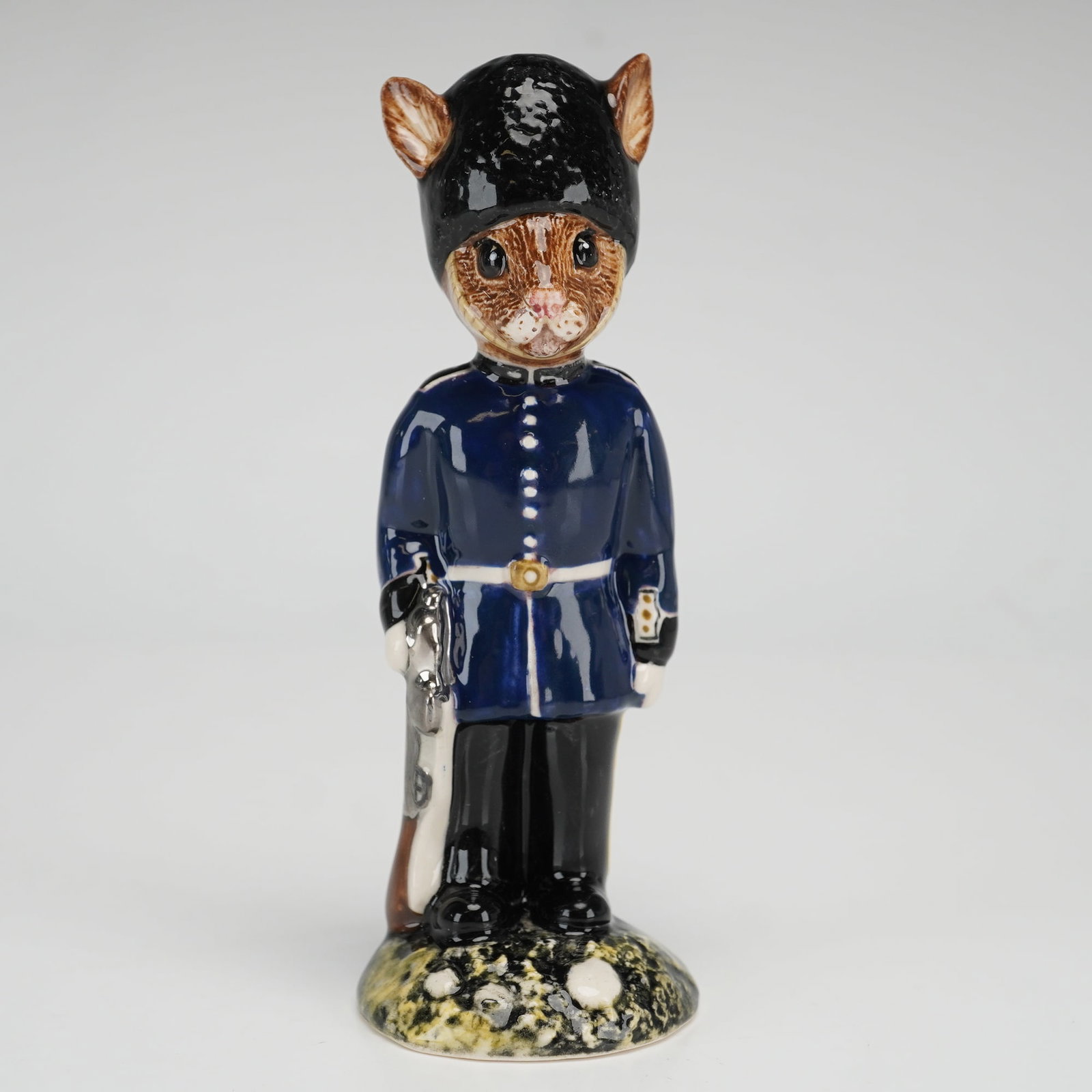 Royal Doulton Prototype Guardsman Bunnykins Figurine: A rare prototype Royal Doulton figurine, Guardsman Bunnykins. The figure is dressed in a blue uniform jacket with white buttons and detailing, and black trousers with yellow stripes on each side. The 