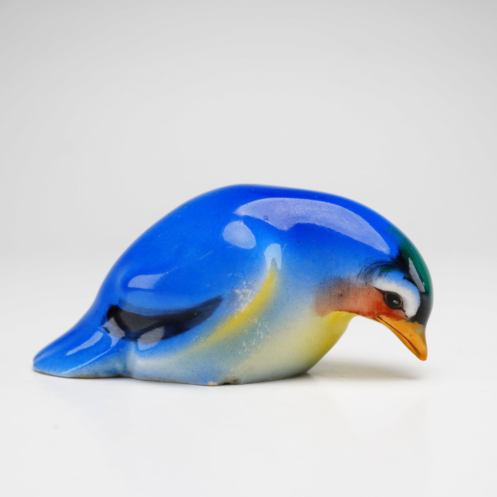 Royal Doulton Bird Figurine, Fledgling HN137B: Style two, blue and yellow coloration with black tips on the wings and a brown beak. Royal Doulton backstamp. Model 1238. Dimensions: 2.75"L x 1.25"W x 1.25"H Date or Era: 1917-1936 Manufacturer or Br