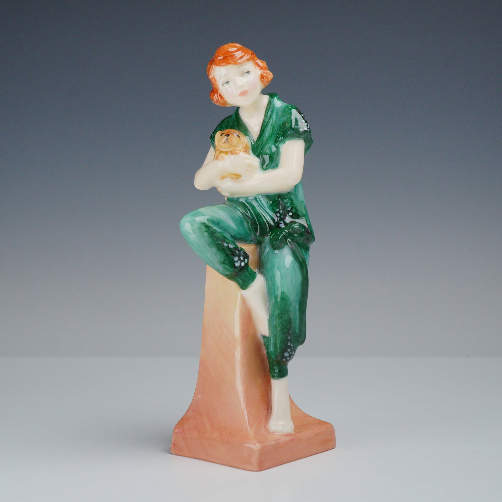 Royal Doulton Exhibition Only Figurine, Lido Lady: This Royal Doulton porcelain figurine is titled Lido Lady and is part of the Archives Bathers Collection. The piece depicts a young woman with reddish-orange hair seated on a tall, square, peach-color