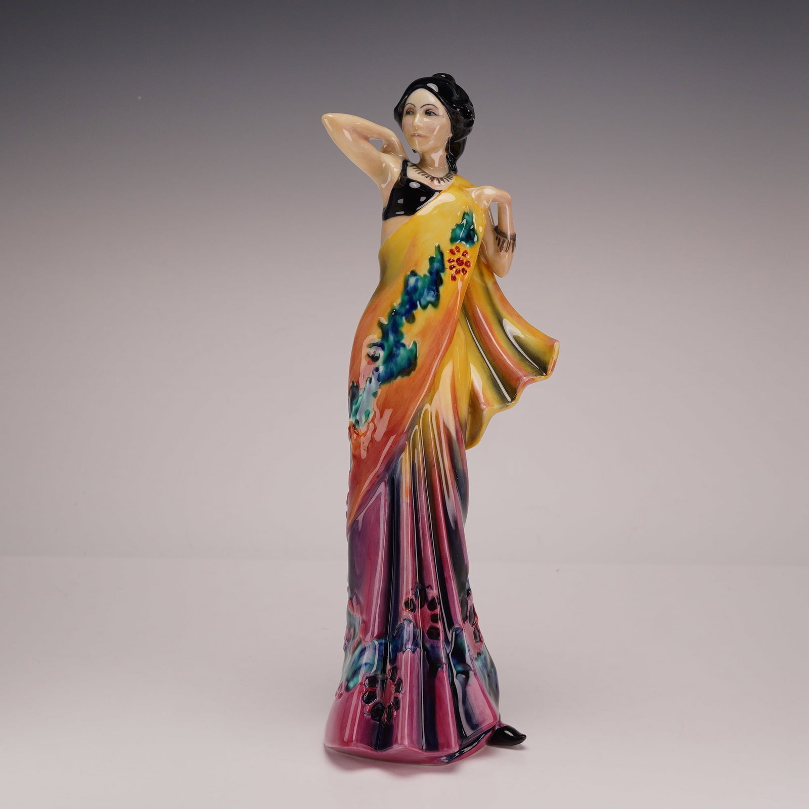 Royal Doulton Prototype Figurine, Eastern Grace HN3683: The figure depicts a woman in a traditional Indian sari in a standing pose with her right arm raised behind her head and her left hand grasping the fabric of her garment. She wears a black sleeveless 