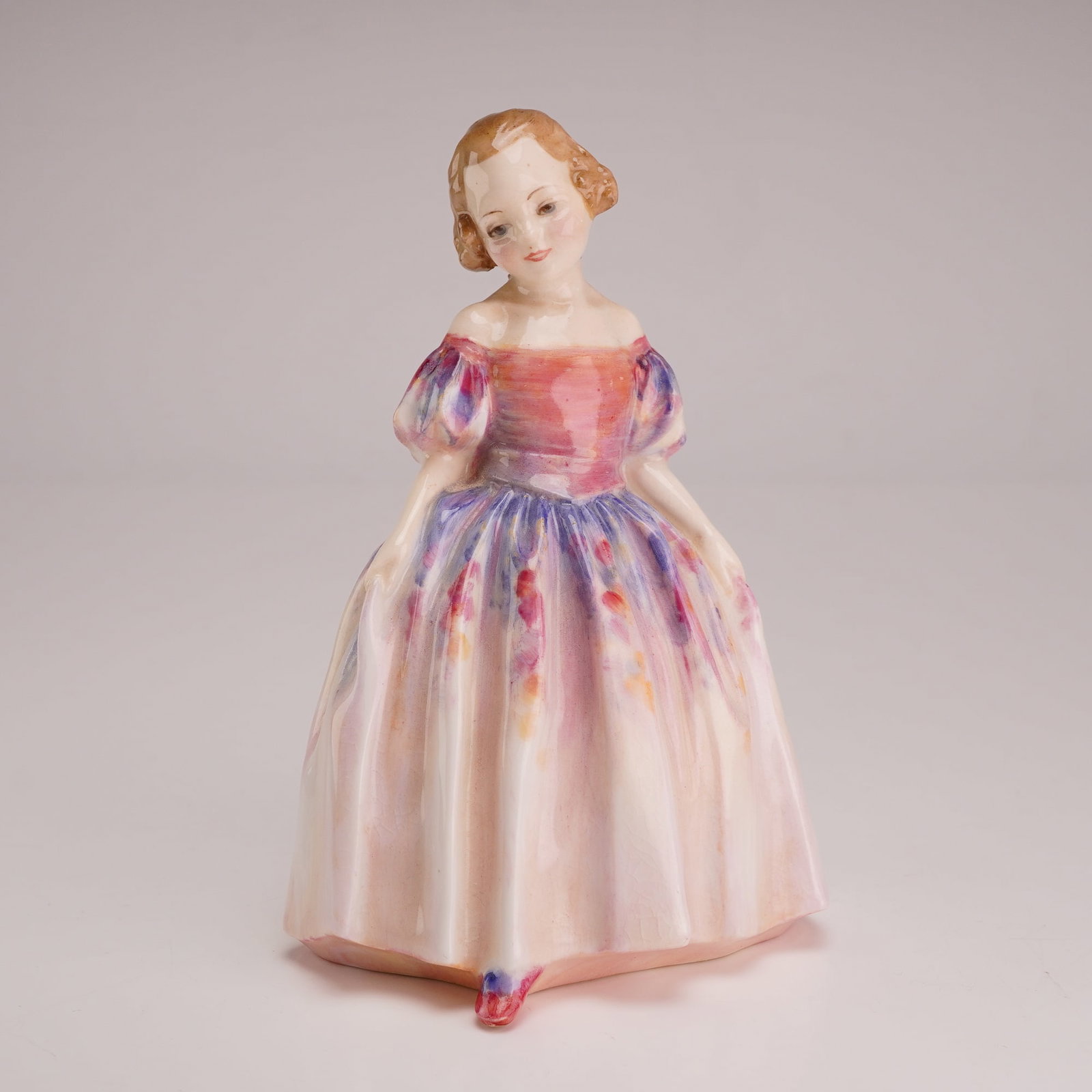 Royal Doulton by Leslie Harradine Figurine, Marie HN1635, Rare Version: Depicts a young girl in a mid-19th-century style dress. The figure is constructed of polychrome glazed porcelain and features light brown hair with a gown consisting of a pink bodice, puff sleeves, an