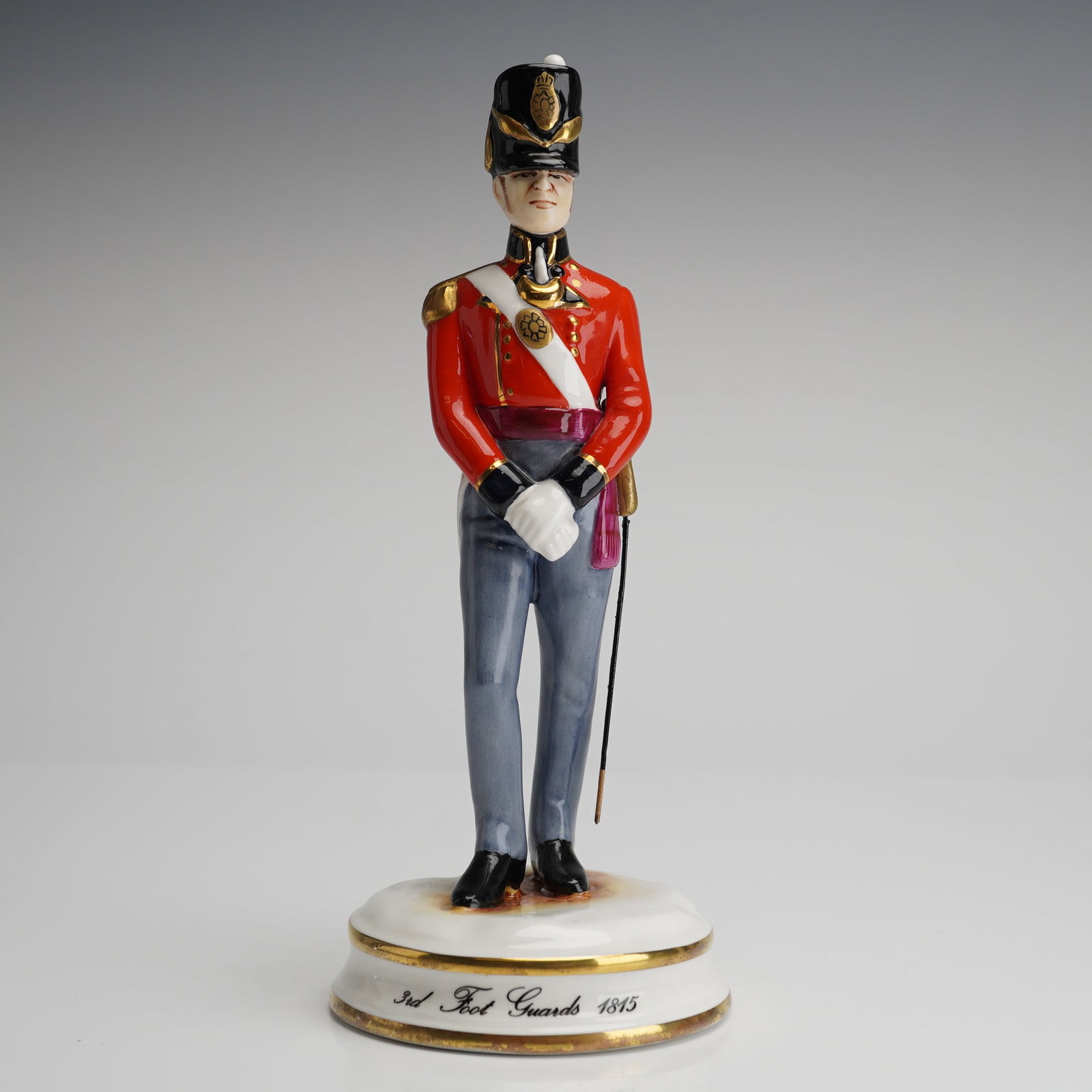 Michael Sutty Porcelain Figurine of the 3rd Foot Guards 1815: A single hand-painted glazed porcelain figurine by Michael Sutty, depicting a soldier of the 3rd Foot Guards 1815 standing at attention. The figure is dressed in a historic uniform featuring a bright 