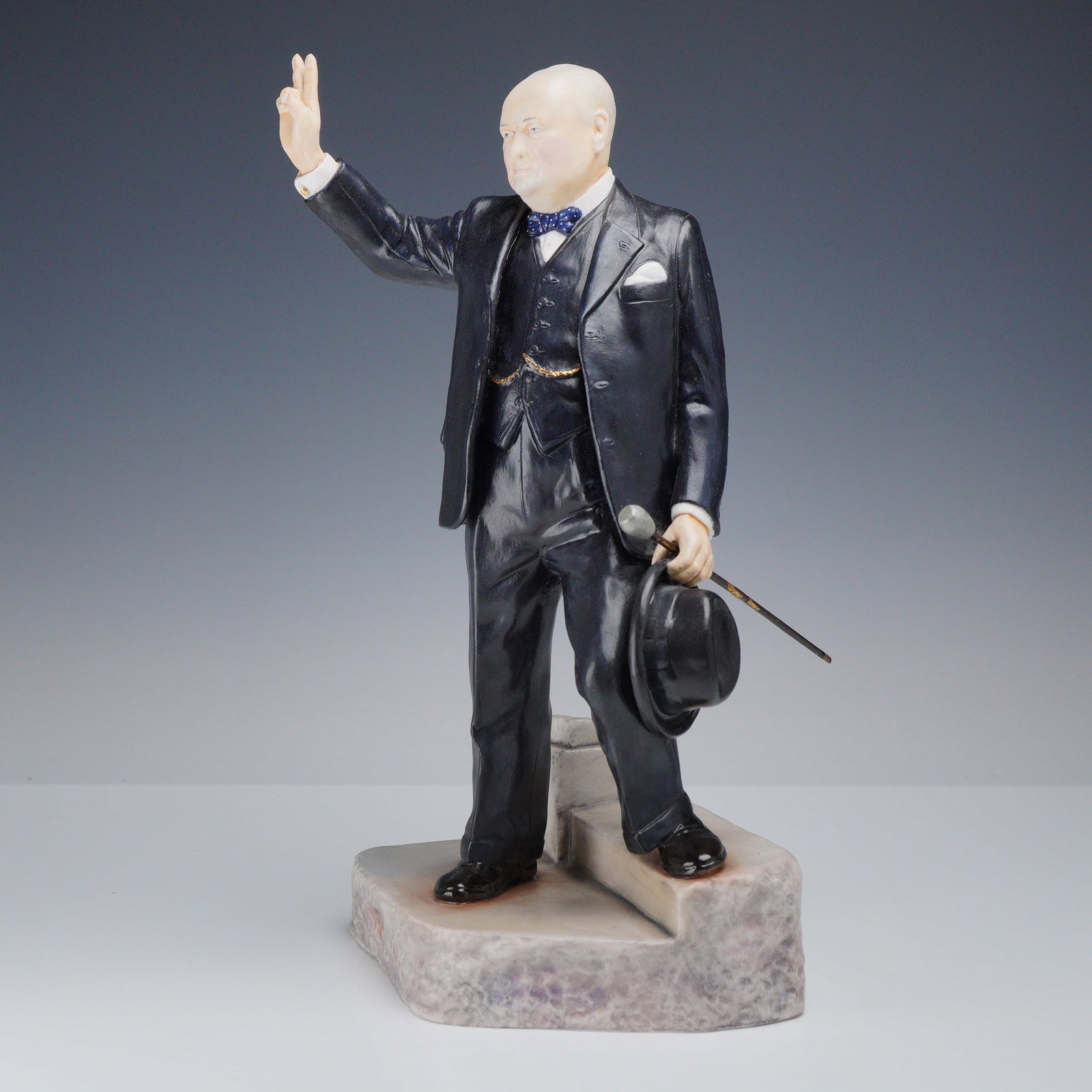 Bronte Fine Bone China Figurine, Sir Winston Churchill: This hand-painted limited edition, 21 of 100, figure depicts Sir Winston Churchill standing on a base modeled as mottled gray stone steps. He is shown wearing a dark gray three-piece suit, a white shi