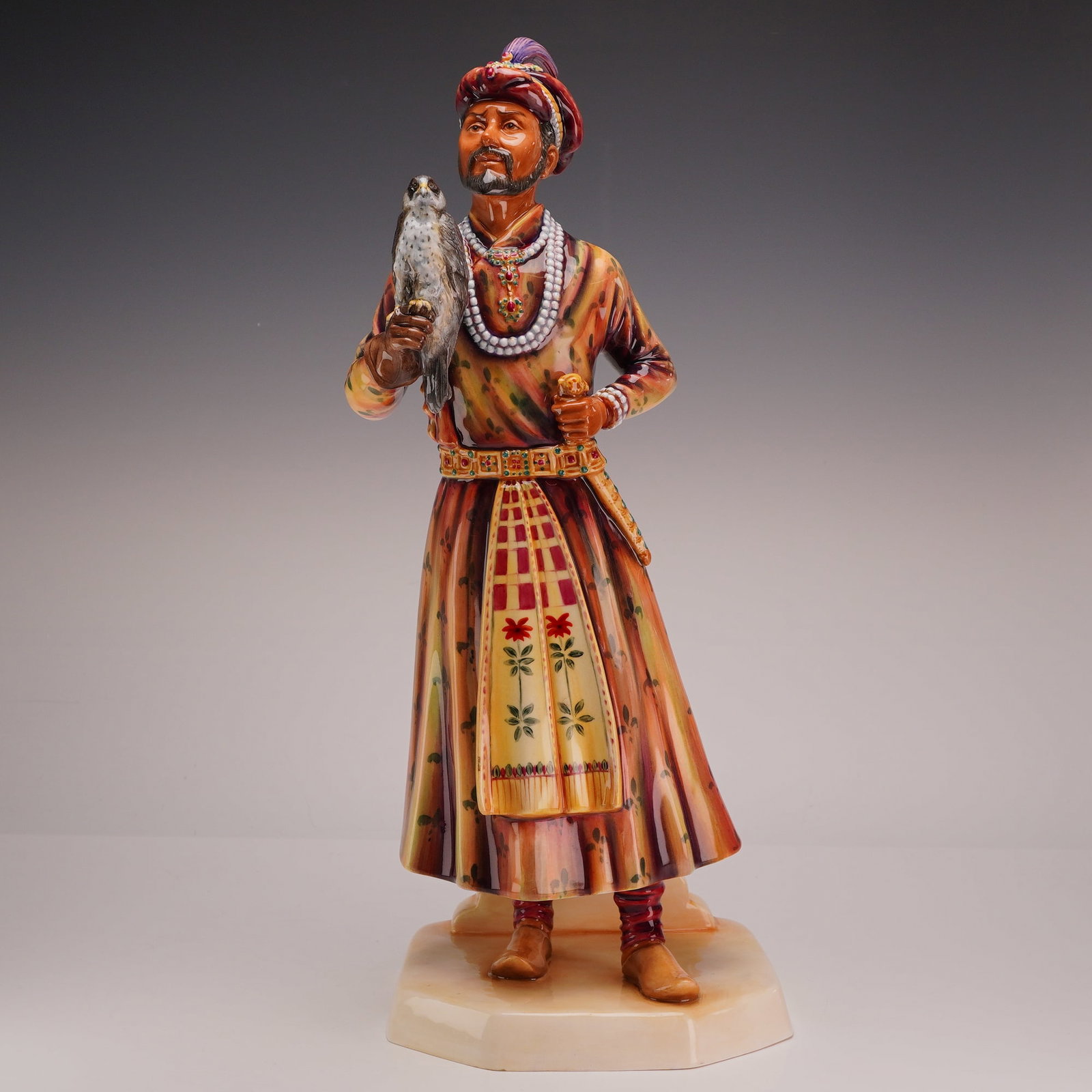 Royal Doulton Prototype Bone China Figurine, Mogul HN5208: This Royal Doulton sculpture, titled The Moghul (model HN5208), is a hand-painted fine bone china figurine. The piece depicts a standing male figure in traditional South Asian courtly dress, featuring