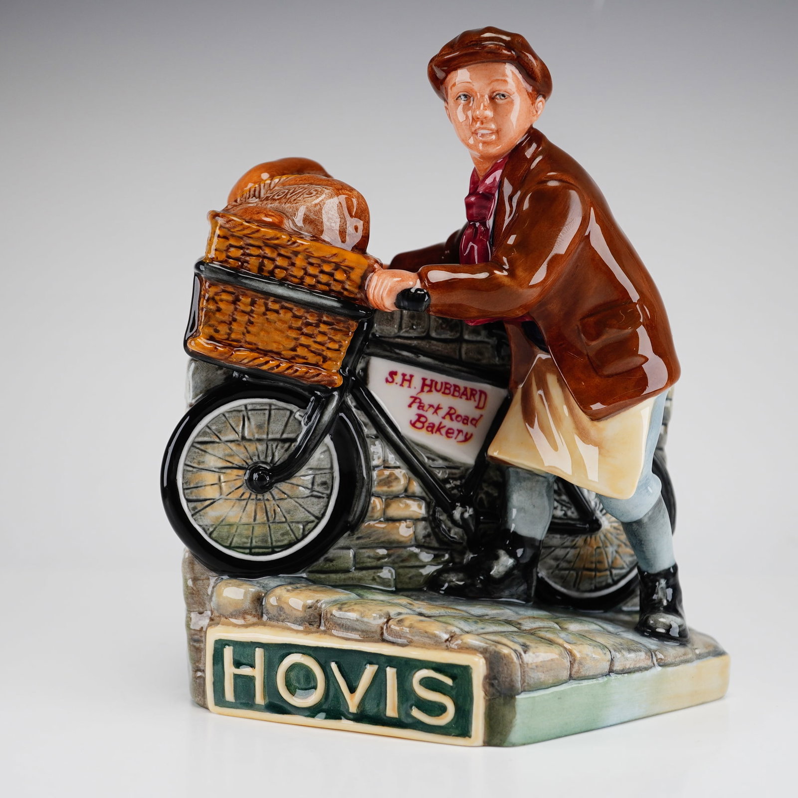 Royal Doulton Limited Edition Figurine, The Hovis Boy MCL 27: This Royal Doulton figurine, titled The Hovis Boy, is a limited edition advertising piece identified as model MCL 27. The polychrome glazed ceramic figure depicts a young delivery boy in early 20th-ce