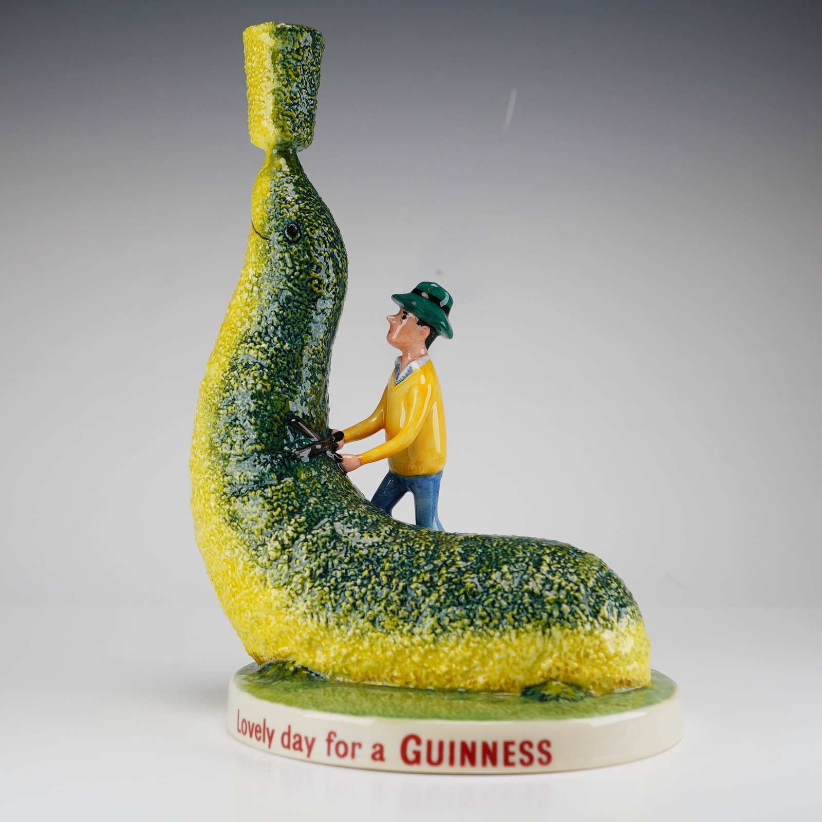 Royal Doulton Guinness Topiary Sea Lion Limited Edition Advertising Figurine MCL 28: This Royal Doulton figurine, model MCL 28, is titled Guinness Topiary Sealion and was produced as a limited edition. The hand-painted glazed porcelain piece depicts a gardener in a yellow sweater, gre