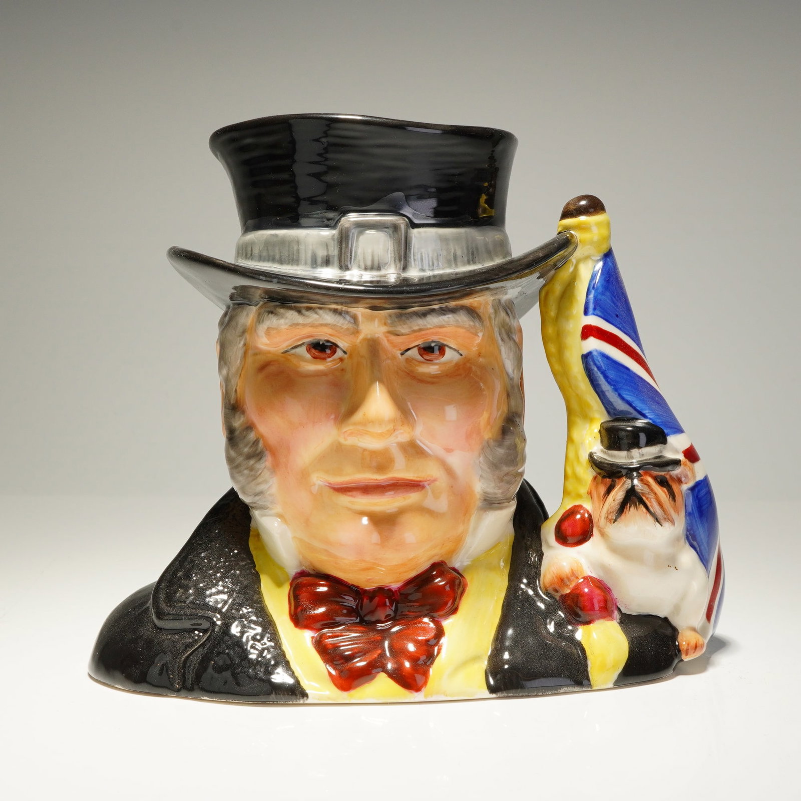 Royal Doulton Prototype Character Jug, John Bull: A rare character jug depicting John Bull, a personification of England, dressed in a black jacket. This distinctive colorway variation showcases detailed craftsmanship, with a handle featuring a Briti