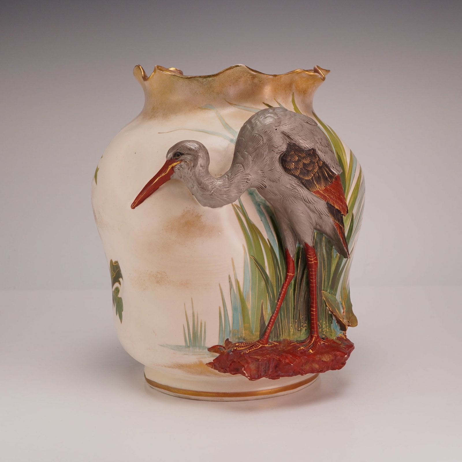 Doulton Burslem High Relief Stork and Hand Painted Floral Vase: This ceramic vase is a Doulton Burslem piece featuring a blush ivory-colored ground and Aesthetic Movement influence. The vessel is designed with a bulbous, squat body and a short neck ending in a wid