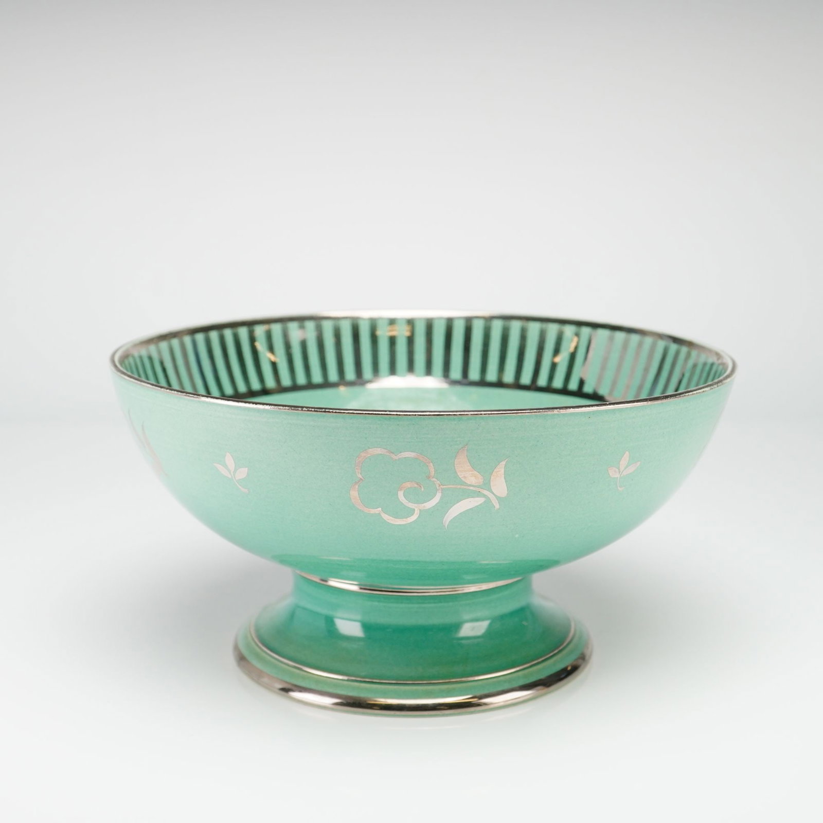 Wedgwood Art Deco Seafoam Green and Silver Luster Footed Bowl: This Wedgwood glazed earthenware footed bowl, likely creamware or pearlware, features a seafoam green glaze accented with silver luster decoration. The vessel is designed as a wide, shallow circular b