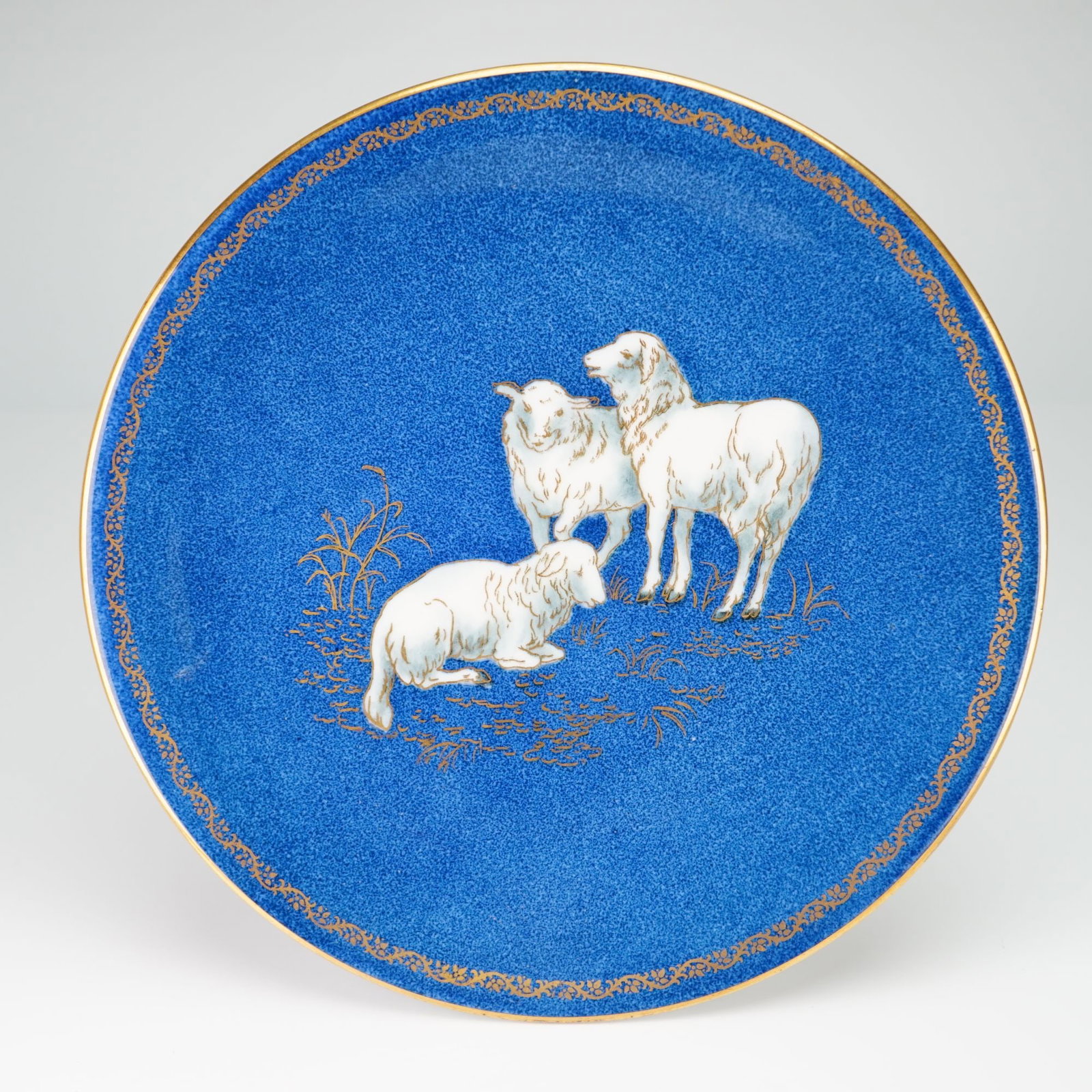 Wedgwood Blue Lustre Porcelain Cabinet Plate with Sheep Motif from the Rubin Collection: This Wedgwood cabinet plate features a mottled powder blue ground. The central decoration consists of three sheep in a landscape, hand-detailed with gilded grasses and plants. The wide rim is finished