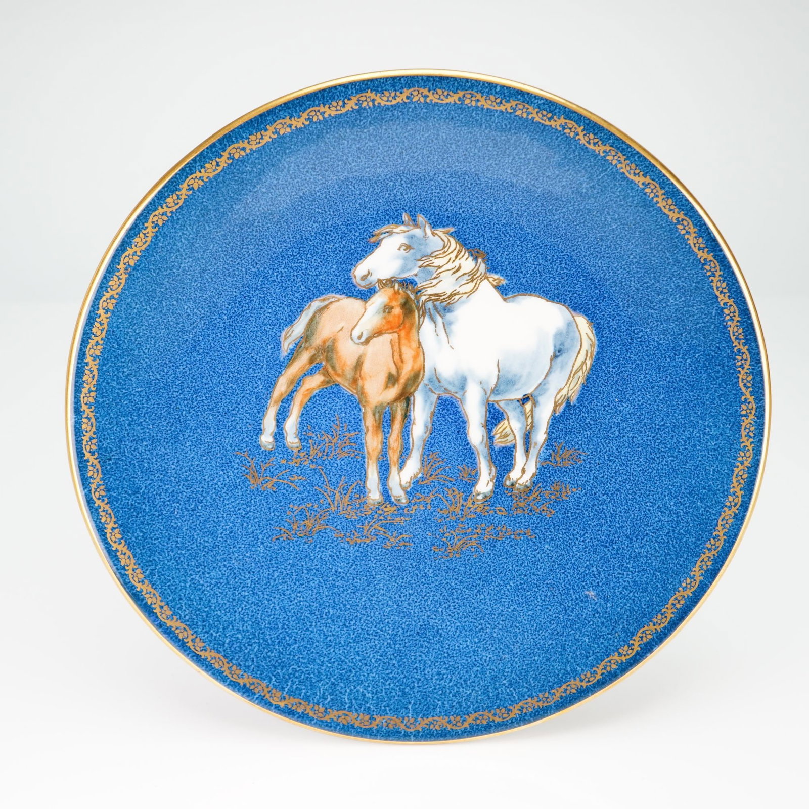 Wedgwood Blue Lustre Porcelain Horse Motif Cabinet Plate from the Rubin Collection: This circular porcelain cabinet plate is manufactured by Wedgwood of England. The piece features a powder blue ground with a central polychrome motif depicting a white mare and a chestnut foal. The ho