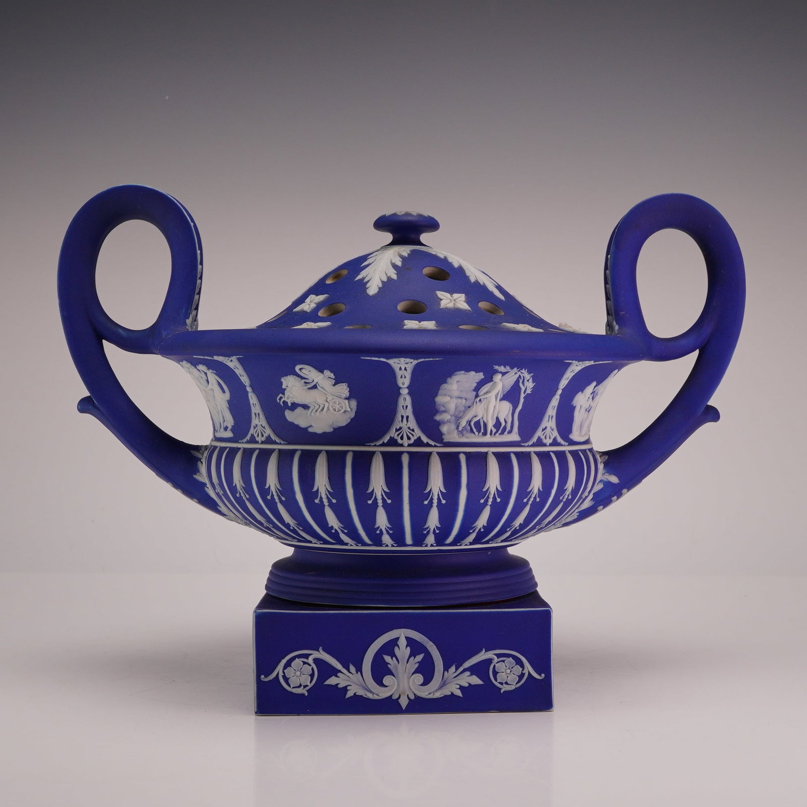 Wedgwood Cobalt Blue Jasperware Potpourri Krater with Pierced Lid: This 19th century Wedgwood cobalt blue jasperware potpourri urn is designed in the form of a neoclassical krater. The stoneware piece features a wide, bowl-shaped body with two large, upright loop han
