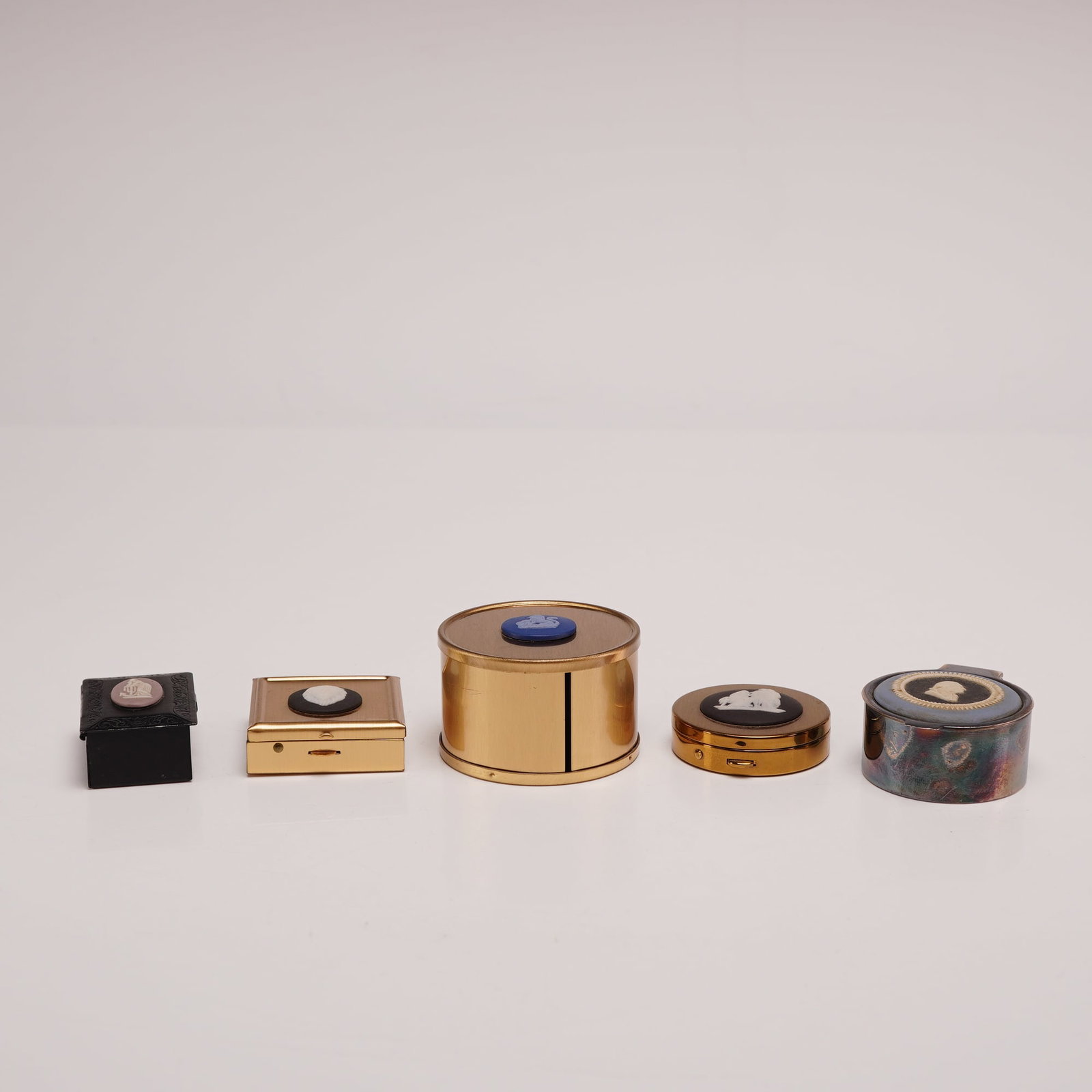 Five Metal Decorative Boxes with Wedgwood Jasperware Insets: An assortment of five decorative boxes featuring stoneware jasperware cameo insets in various colors and designs, all bearing labels for the Rubin Collection. The group includes a black composition sq