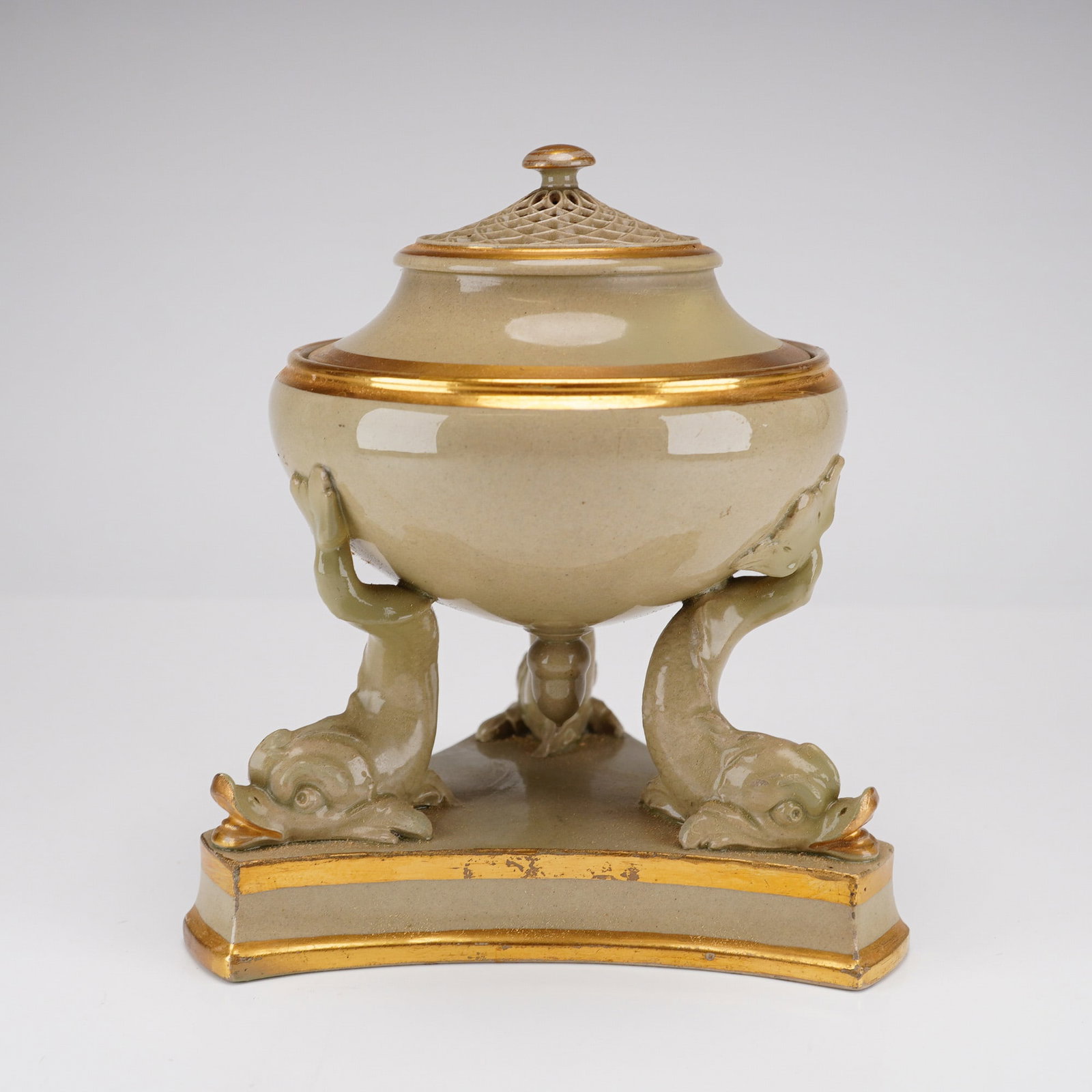 Wedgwood Drabware Dolphin Pastille Burner with Pierced Lid and Gilt Detailing: A Wedgwood drabware ceramic pastille burner featuring a globular bowl supported by three stylized dolphins. The vessel rests on a concave triangular tripod base. The piece is finished in a matte olive