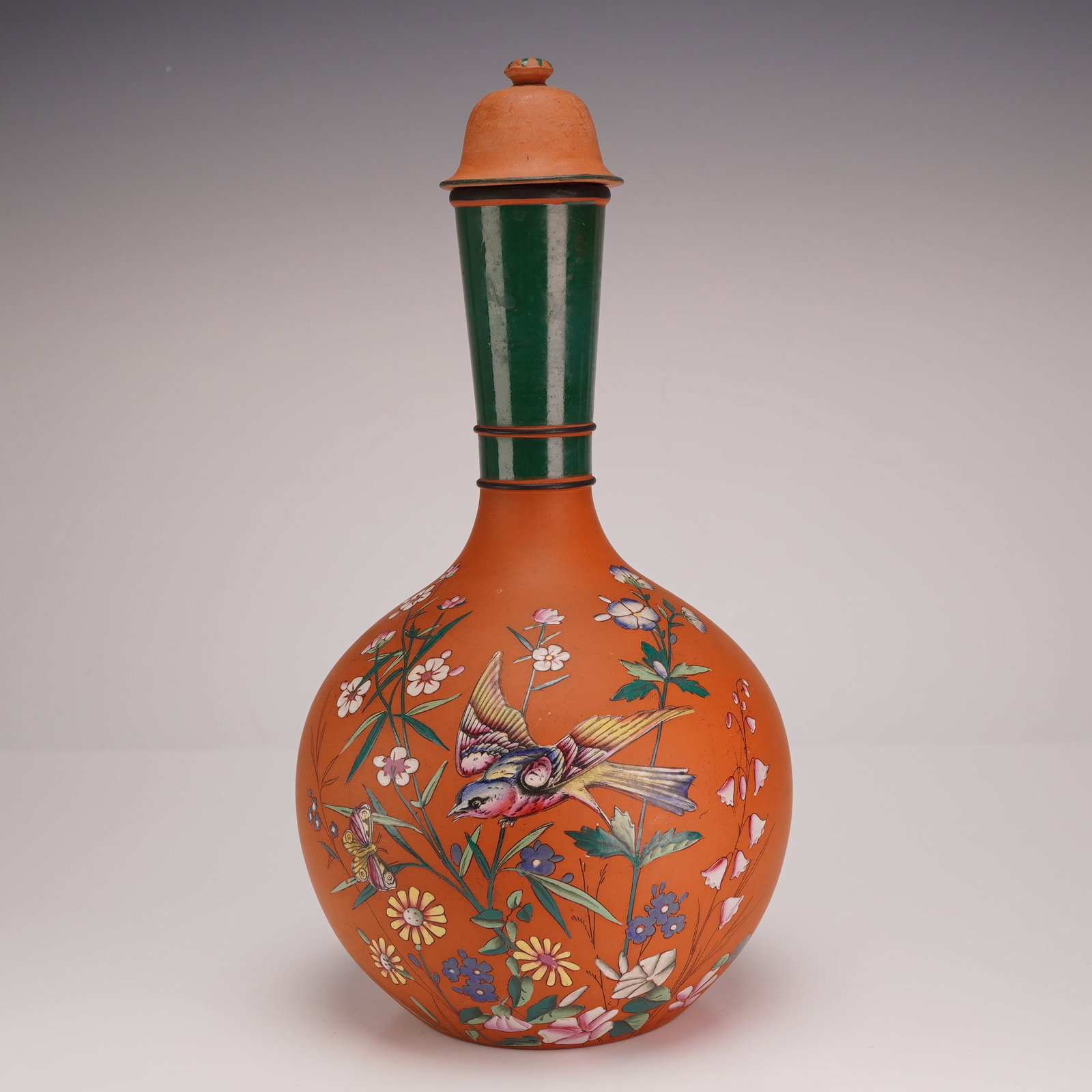 Wedgwood Rosso Antico Enameled Water Bottle and Stopper: A Wedgwood Rosso Antico unglazed red stoneware water bottle and matching stopper. The vessel features a globular body with a tall, slightly tapering cylindrical neck and a bell-shaped stopper topped w