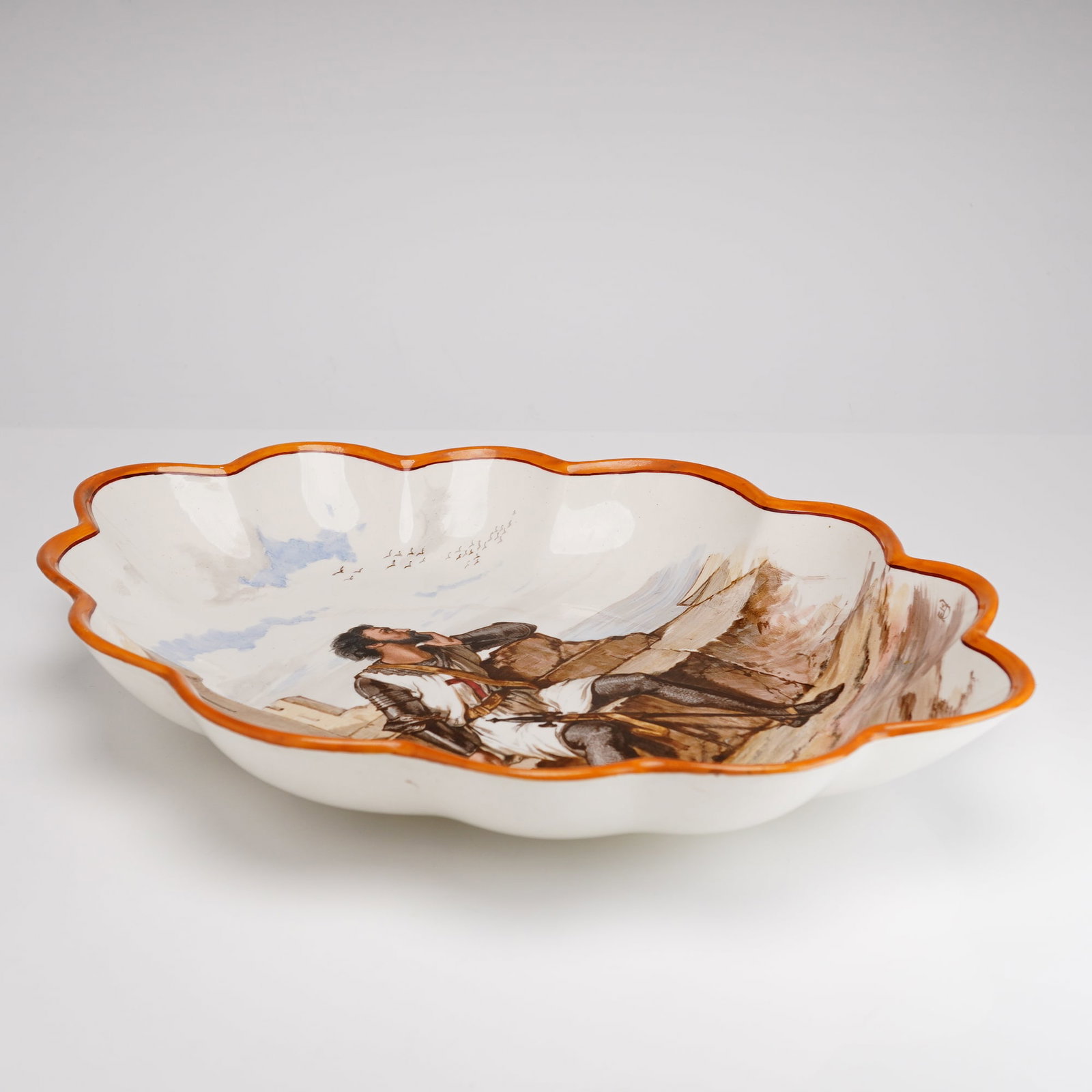 Wedgwood Hand-Painted Creamware Scalloped Bowl Featuring a Knight in Armor, 19th Century: A fine earthenware or creamware lobed oval charger produced by Josiah Wedgwood and Sons, dating to the 19th century. The vessel features a deeply scalloped rim accented with a hand-painted orange enam