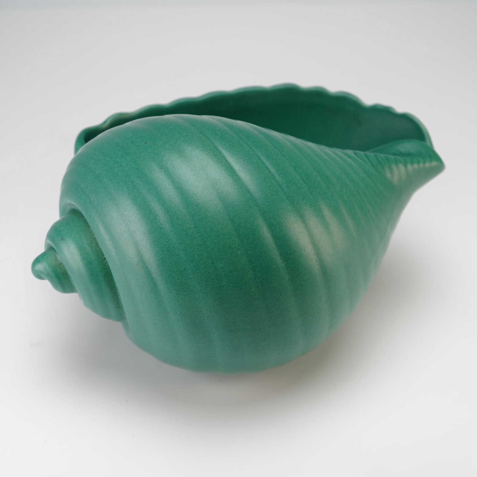 Wedgwood Etruria England Matt Green Conch Shell Planter Designed by Keith Murray circa 1935: A Wedgwood ceramic planter modeled in the form of a conch shell, designed by Keith Murray circa 1935. The piece features a naturalistically modeled shell form with a spiral apex and a scalloped rim, f