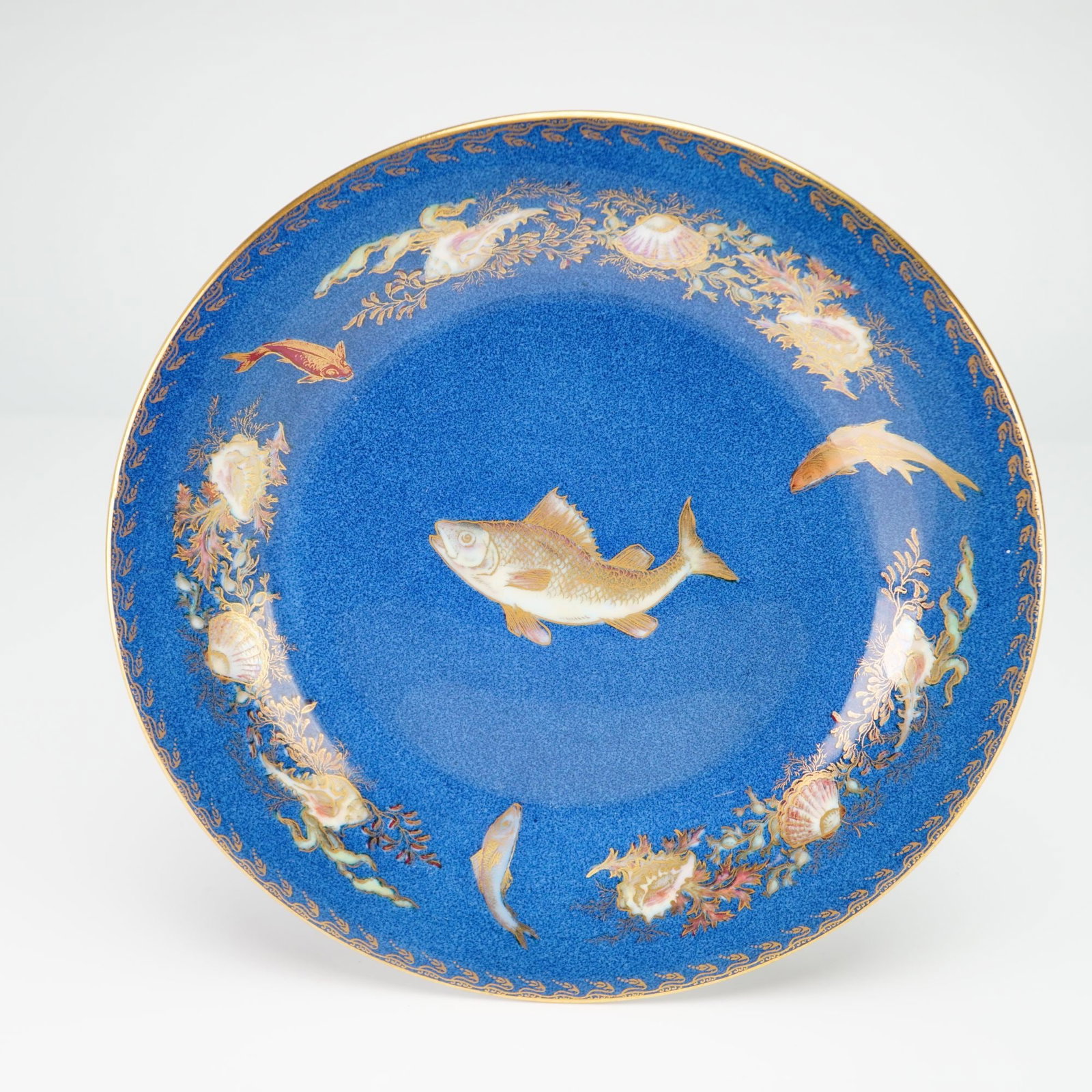 Wedgwood Blue Ground Fish Cabinet Plate from the Rubin Collection: A Wedgwood fine bone china cabinet plate featuring a mottled powder blue ground across the well and rim. The central decoration consists of a single fish rendered in cream and gold tones with hand-pai