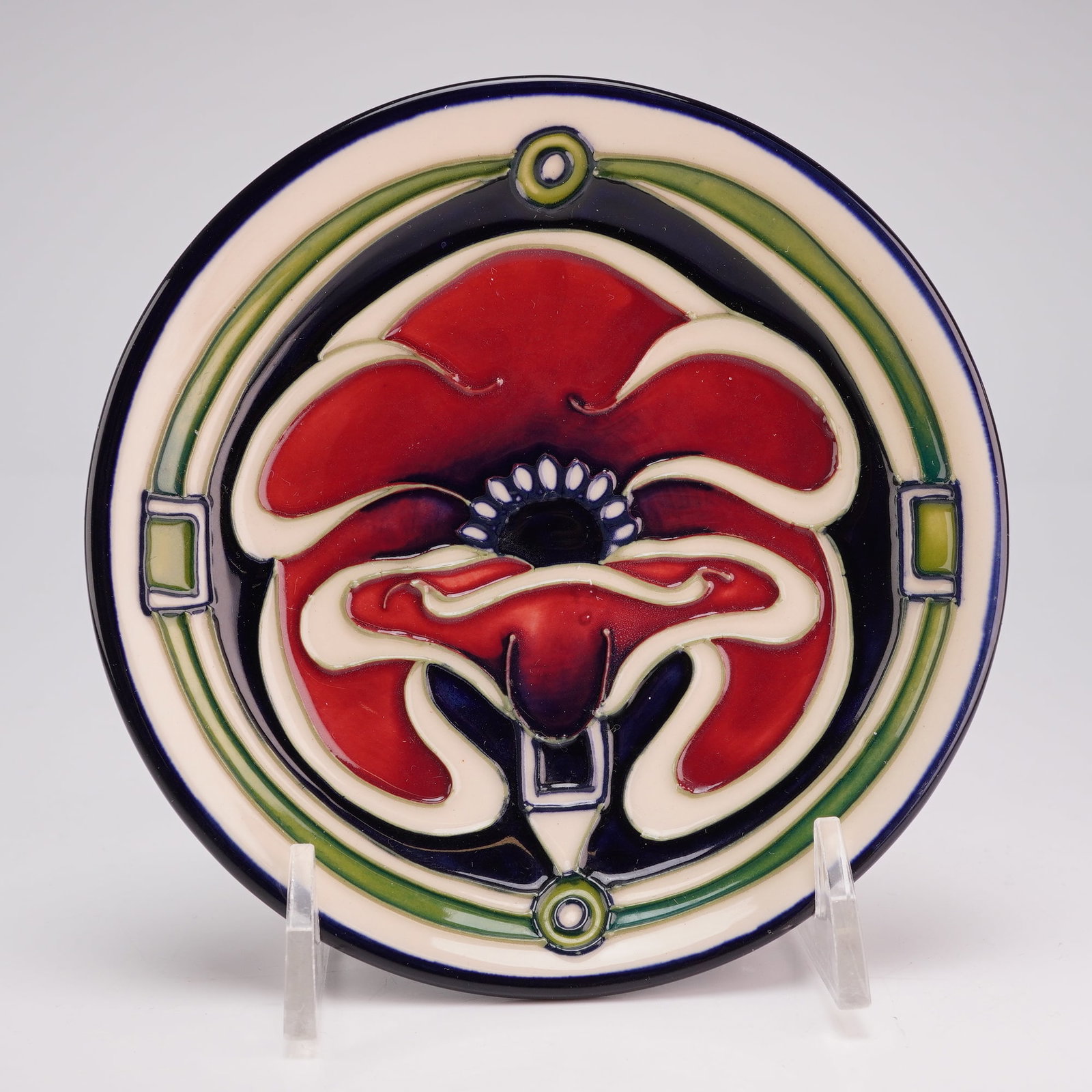 Moorcroft Pottery by Rachel Bishop Pin Dish, Petal Dome: The piece features a central stylized red poppy blossom executed with traditional tube-lined slip outlines. The floral motif is set against a deep cobalt blue ground and is framed by a geometric borde