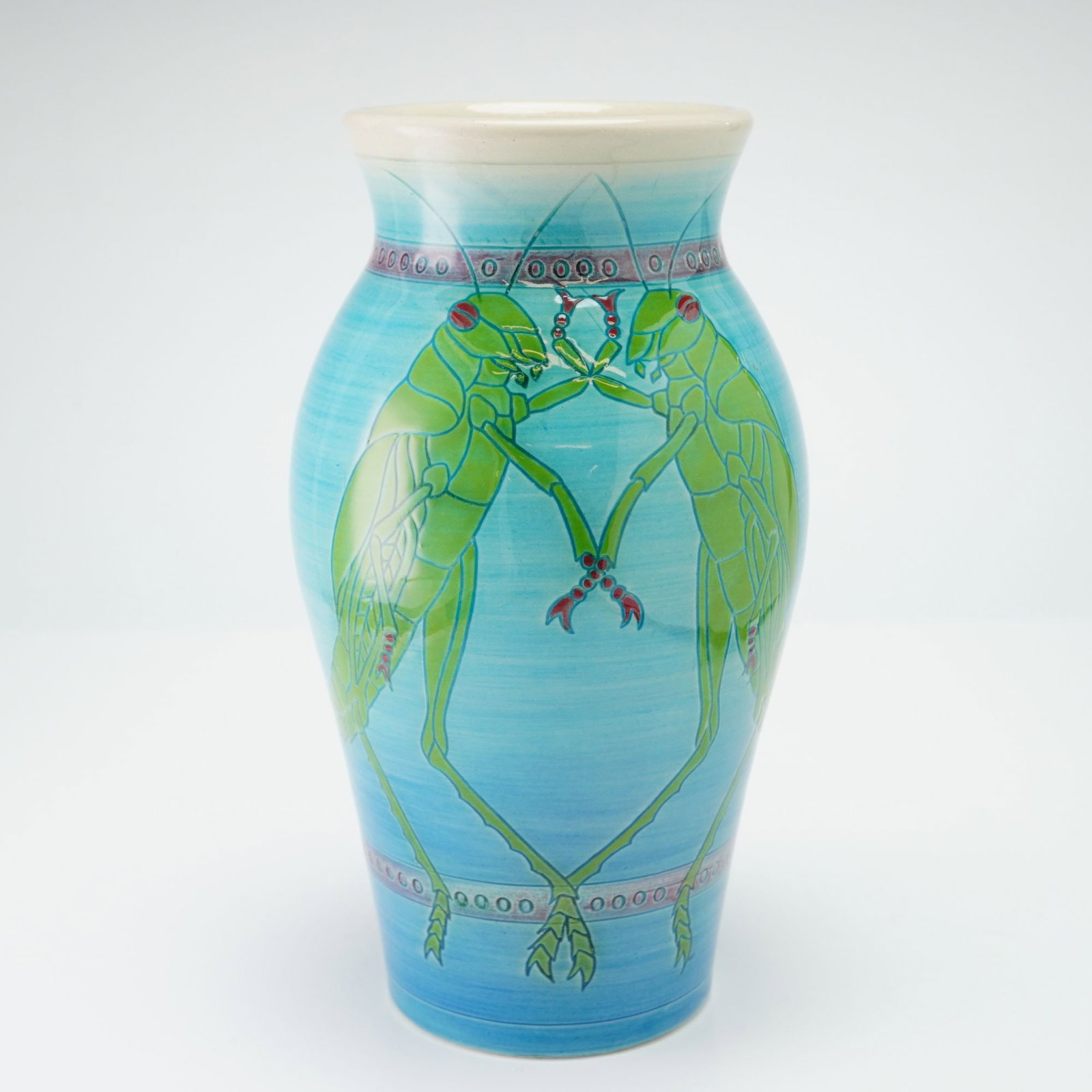 Dennis China Works Pottery by Sally Tuffin Grasshopper Vase: The baluster-form vessel is decorated with two pairs of stylized green grasshoppers with red accents. The background features a turquoise-blue glaze with visible horizontal brushstroke textures. Two d