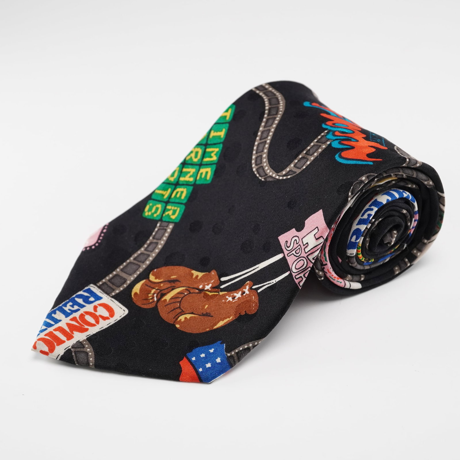 Nicole Miller HBO Television Theme Necktie: This Nicole Miller HBO television theme necktie features a vibrant allover print incorporating classic HBO channel graphics, movie reels, boxing gloves, award statuettes, and retro broadcast imagery. 