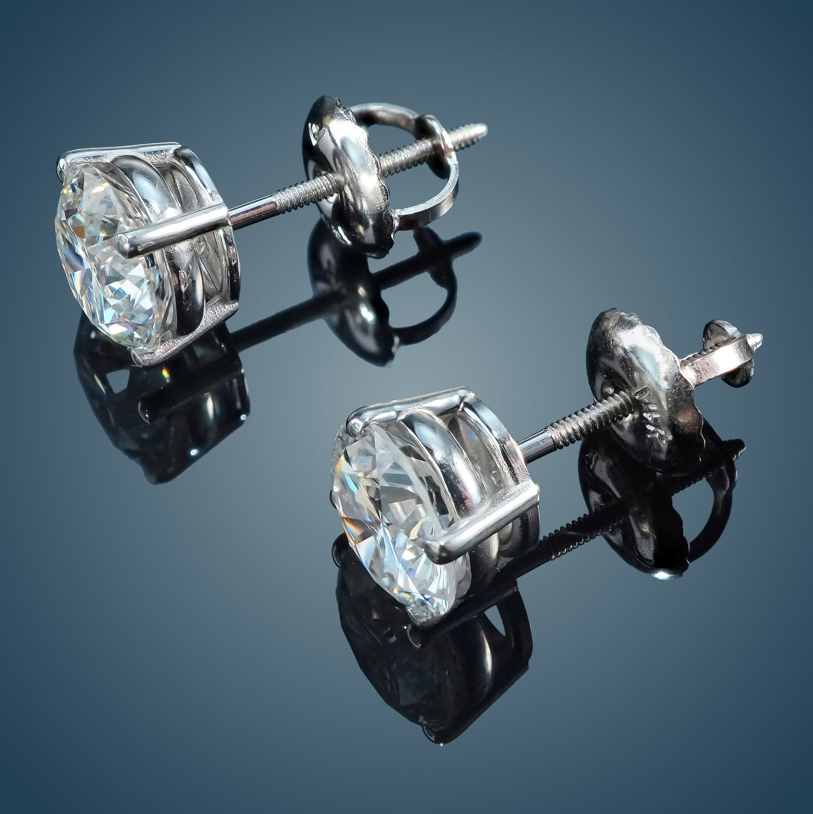 Pair of 14K White Gold and 1.80ctw Diamond Stud Earrings: These earrings are crafted from 14K white gold and feature a four-prong setting and screw-back design. Each prong holds a round cut lab diamond with E color grade and VS1 clarity. The diamonds have a 