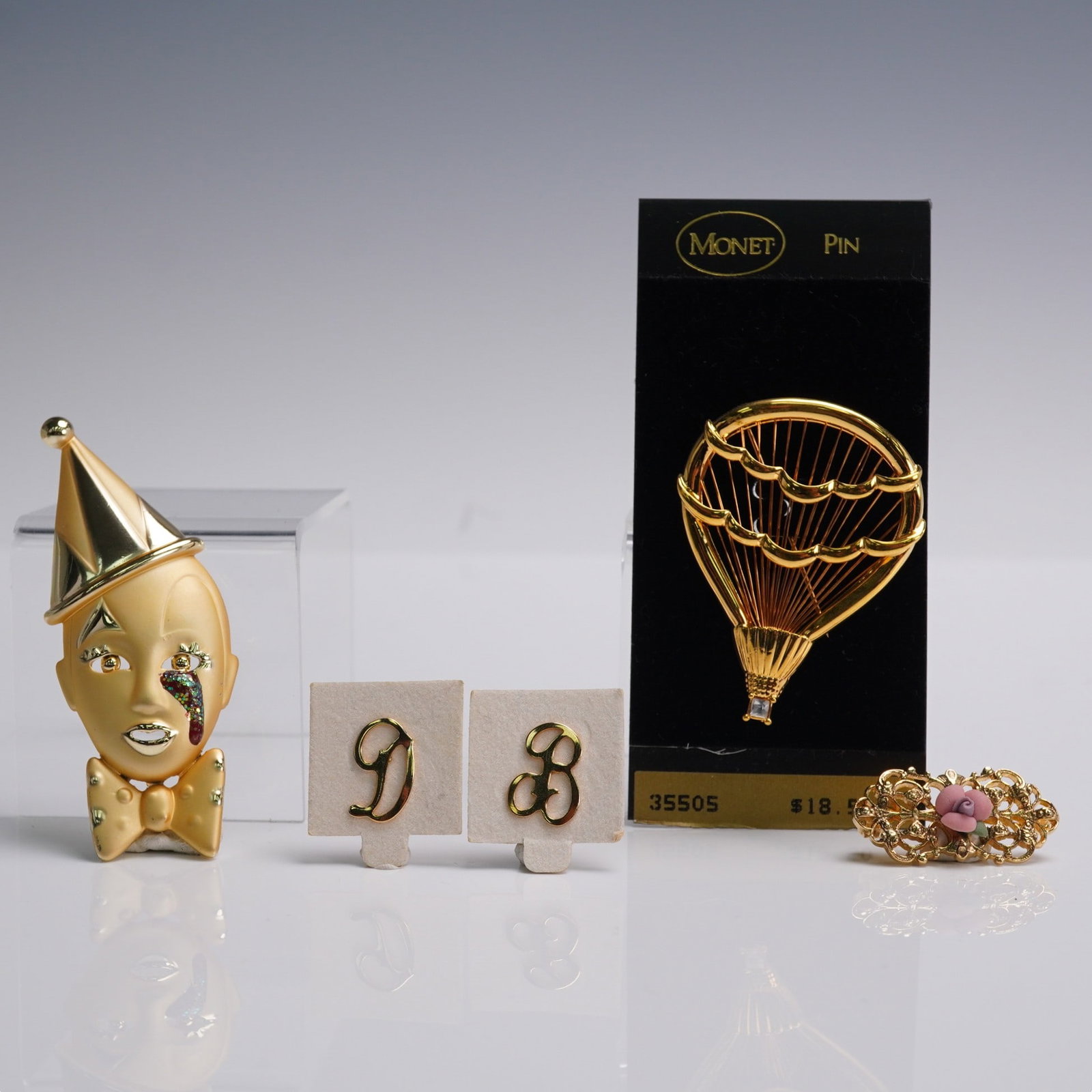 5pc Gold Tone Brooch & Pin Lot incl. Monet & Pierrot: Lot of five decorative gold tone pins and brooches in assorted styles. Includes a tall metallic Pierrot face with pointed hat, a matte enamel clown face with rainbow tear detail, a Monet hot air ballo