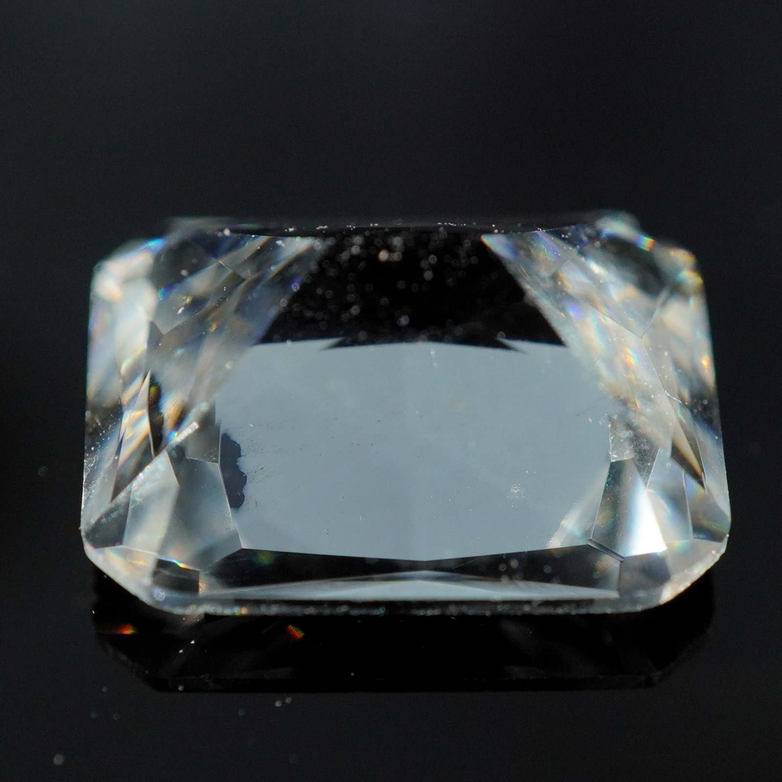 Lindenwold's Faceted Clear Gemstone: A faceted colorless gemstone from Lindenwold's Fine Jewelers, likely a synthetic or simulated diamond, presented in a rectangular brilliant cut. The stone exhibits high clarity and reflective brillian