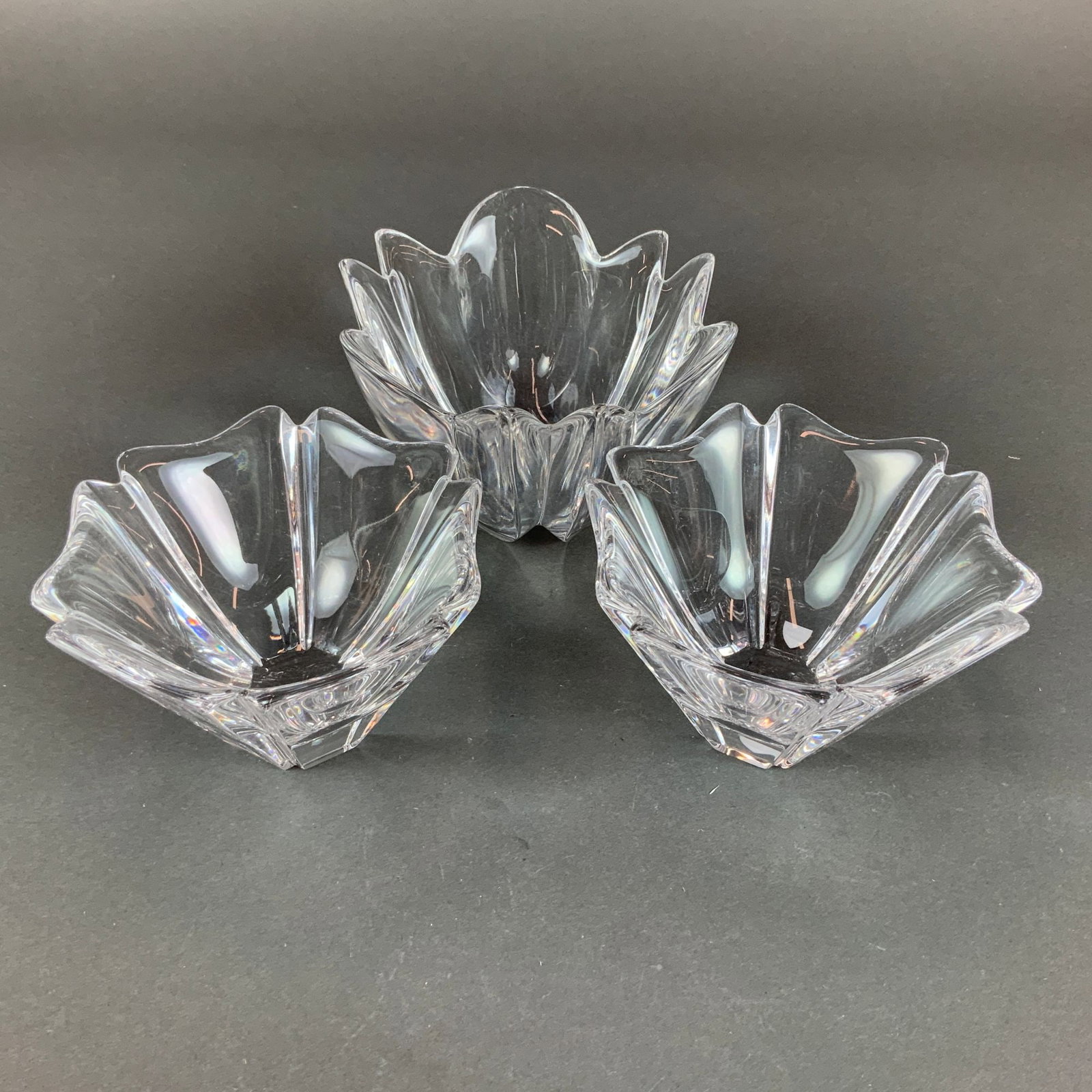 3pc Orrefors Crystal Lily Bowls: A trio of Orrefors crystal lily bowls manufactured in Sweden. This set consists of one larger bowl and two smaller matching bowls. Each piece is crafted from heavy, high-quality clear crystal and feat