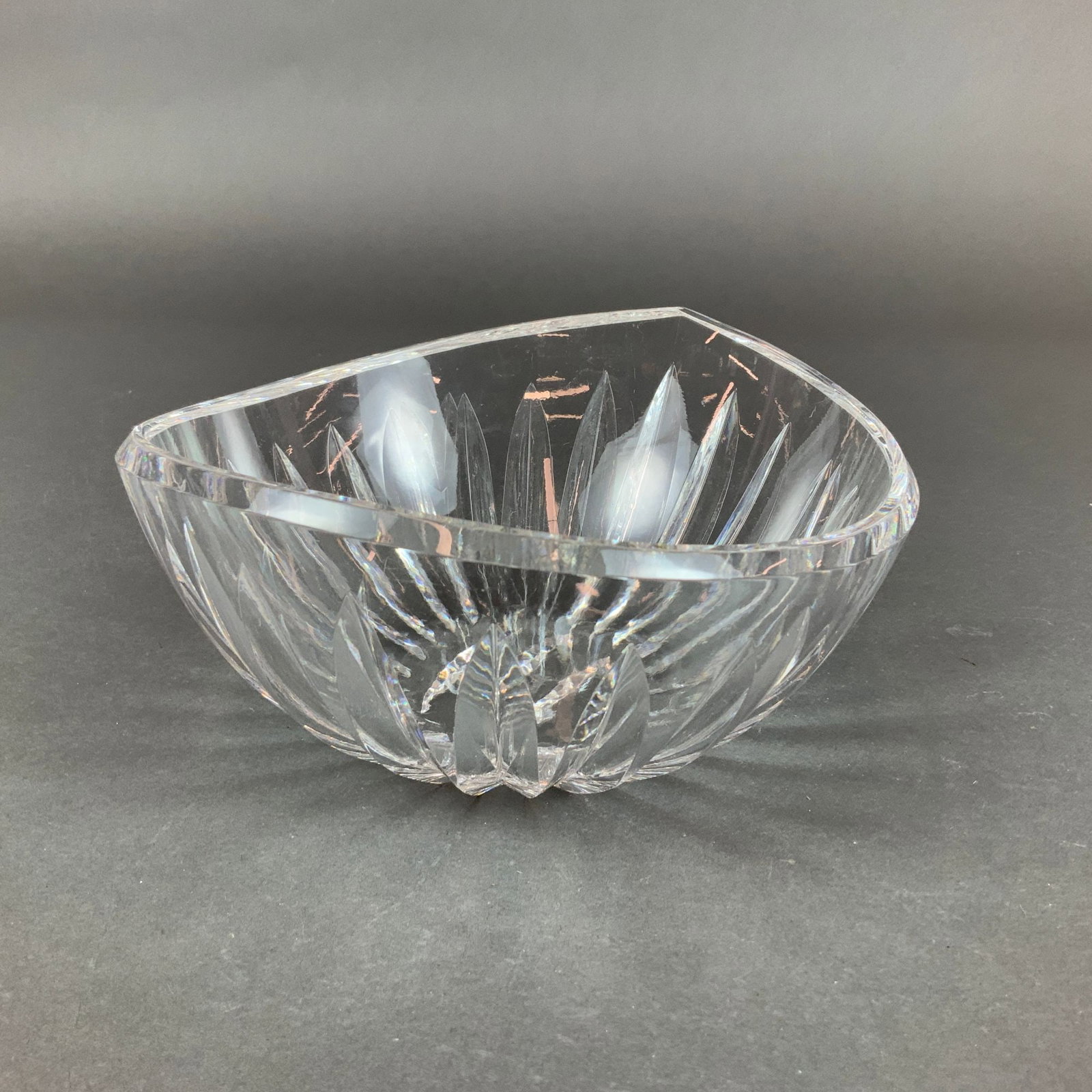 Waterford Crystal Vertical Ribbed Cut Oval Bowl: A Waterford lead crystal oval bowl featuring a slanted, asymmetrical rim. The exterior is decorated with deep vertical wedge cuts that radiate from the base and terminate at a horizontal miter cut enc
