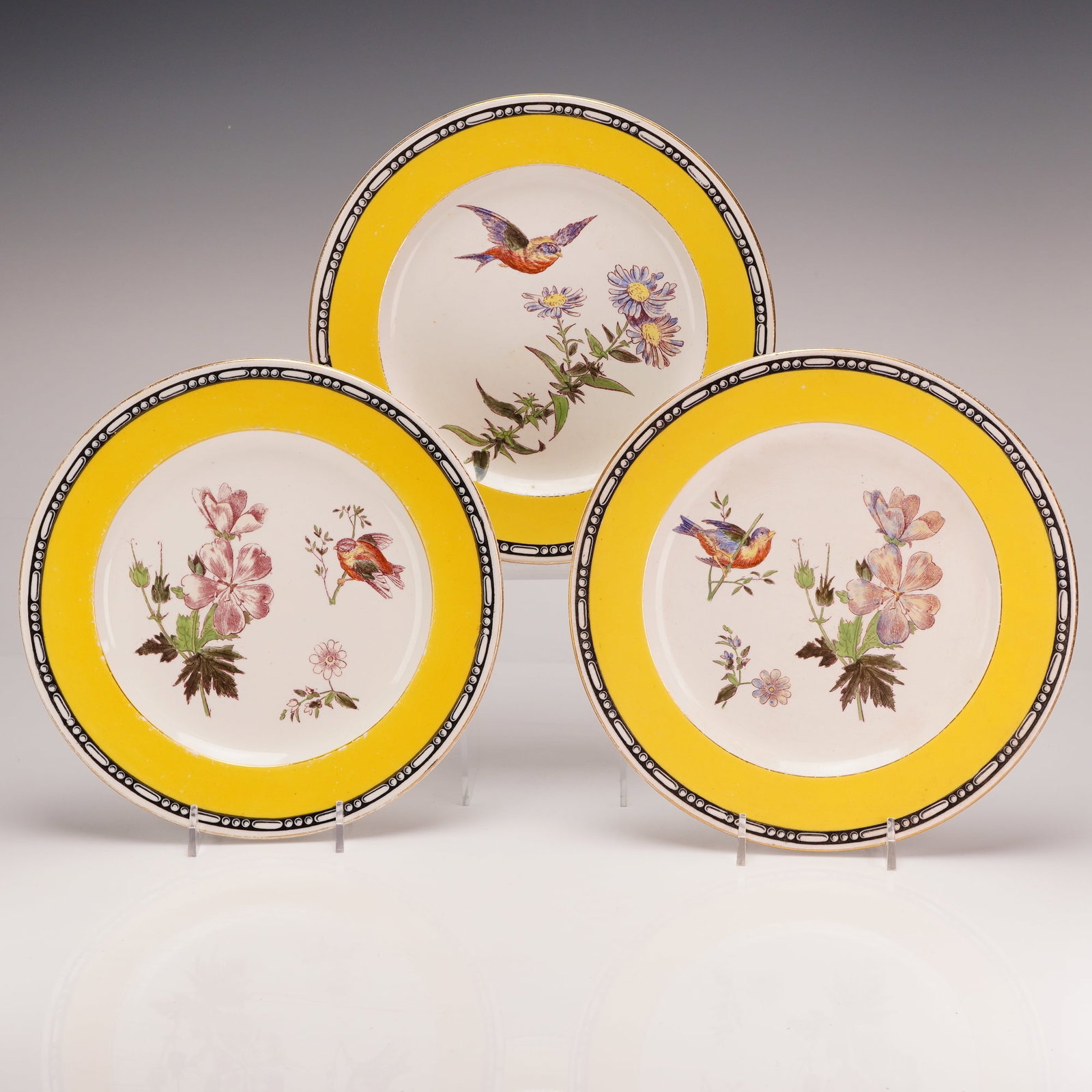 3pc Wedgwood Etruria Earthenware Plates: This trio of circular earthenware plates was produced by Wedgwood at the Etruria works in England. The design follows a Jardin du Roi pattern, featuring a vibrant yellow border framed by a black and w