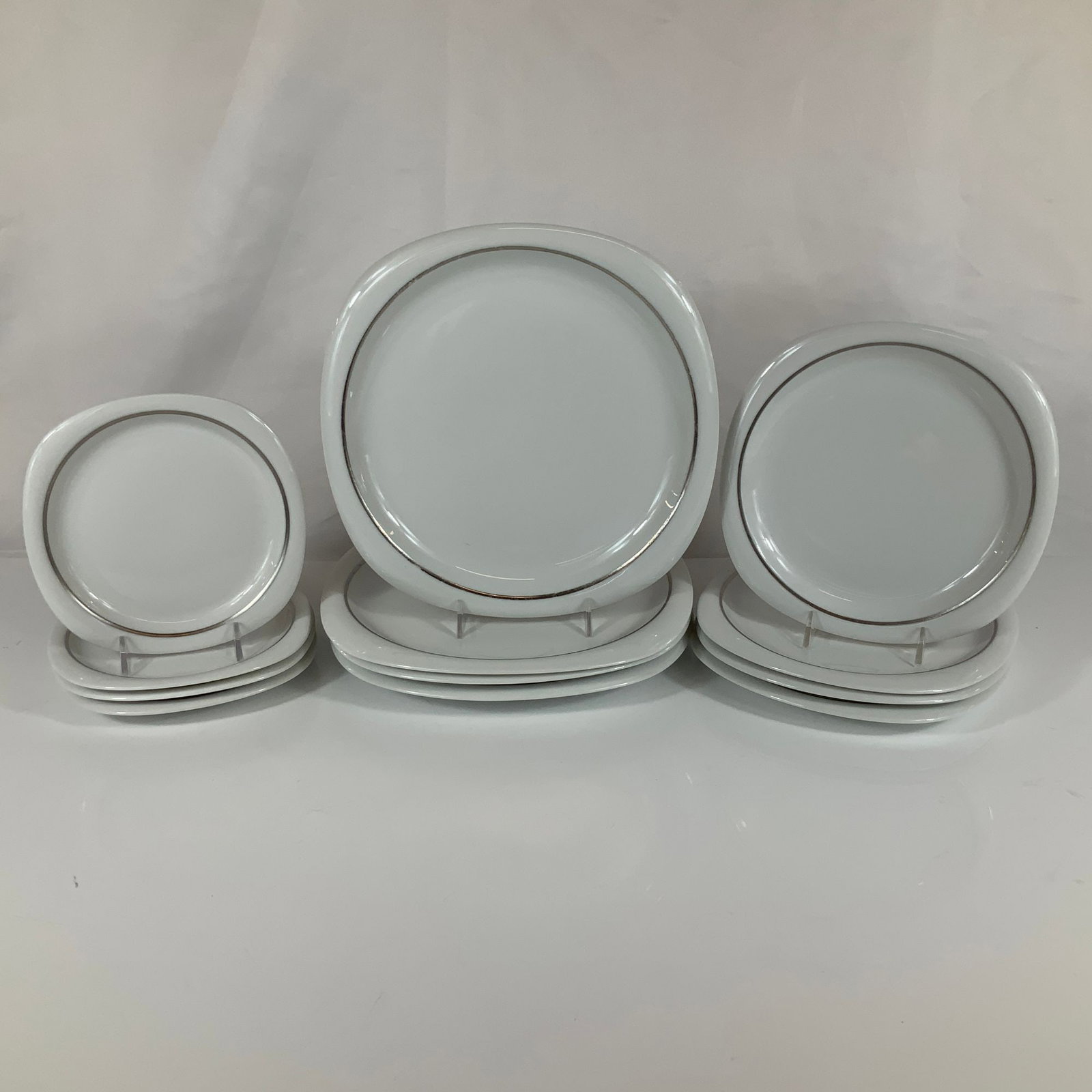 A 12-Piece Set of Rosenthal Studio-Line Suomi Lanka Porcelain Plates: A set of twelve porcelain plates manufactured by Rosenthal as part of the Studio-Line collection. The pieces feature the Suomi shape, characterized by a minimalist Modernist design with a soft square