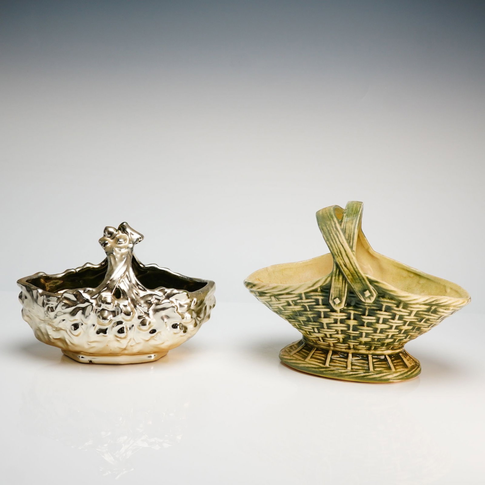 Two McCoy Ceramic Baskets: This lot features two McCoy ceramic baskets. The first is a 1950s McCoy pottery basket in the acorn and oak leaf pattern, featuring a green and cream glazed woven texture and a pedestal base, with an 