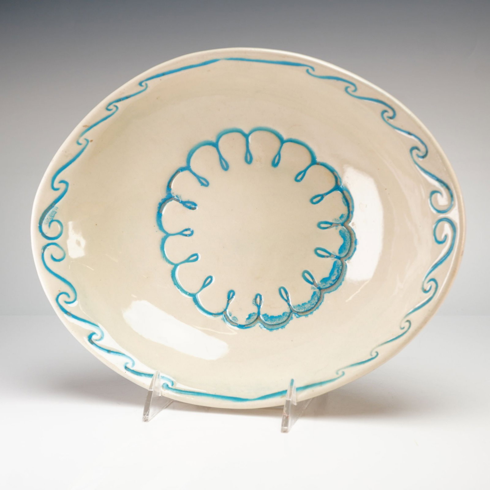 McCoy Decorative White Floral Bowl: McCoy decorative white floral bowl. This glazed ceramic shallow bowl features a cream ground decorated with turquoise blue hand-painted motifs, including a wavy rim border and a central looped circula