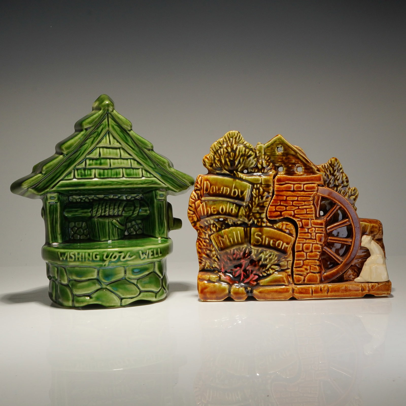 Two McCoy and Ungemach Pottery Figural Ceramic Planters: Two vintage American ceramic planters featuring scenic rural motifs. The first item is a wishing well-form planter finished in a green gloss glaze, featuring the embossed text WISHING YOU WELL on the 