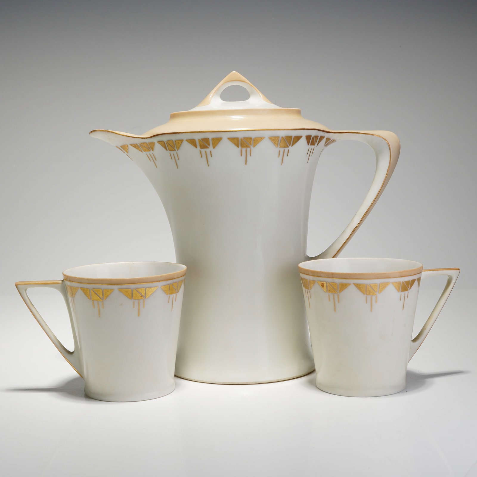 Hutschenreuther Art Deco Porcelain Chocolate Pot and Two Cups: This three-piece Hutschenreuther Bavaria porcelain chocolate service is designed in the Art Deco style, dating to circa 1920"1930. The set consists of a tall, lidded chocolate pot and two matching