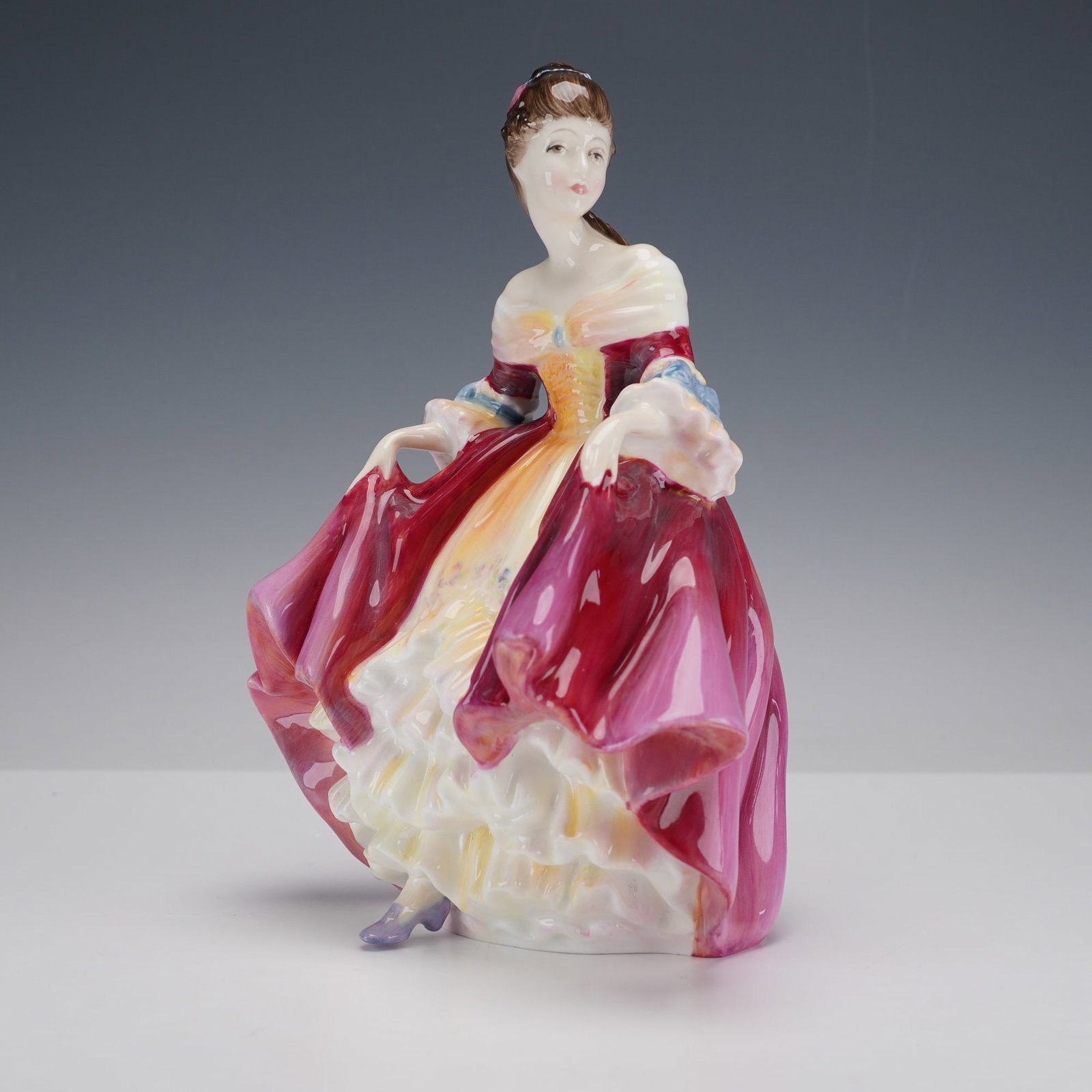 Royal Doulton Figurine, Southern Belle HN2229: A hand painted beauty depicted in a colorful gown holding each side. This graceful lady embodies classic charm. Royal Doulton backstamp. Artist: Peggy Davies Dimensions: 4.25"L x 6"W x 8"H Date or Era