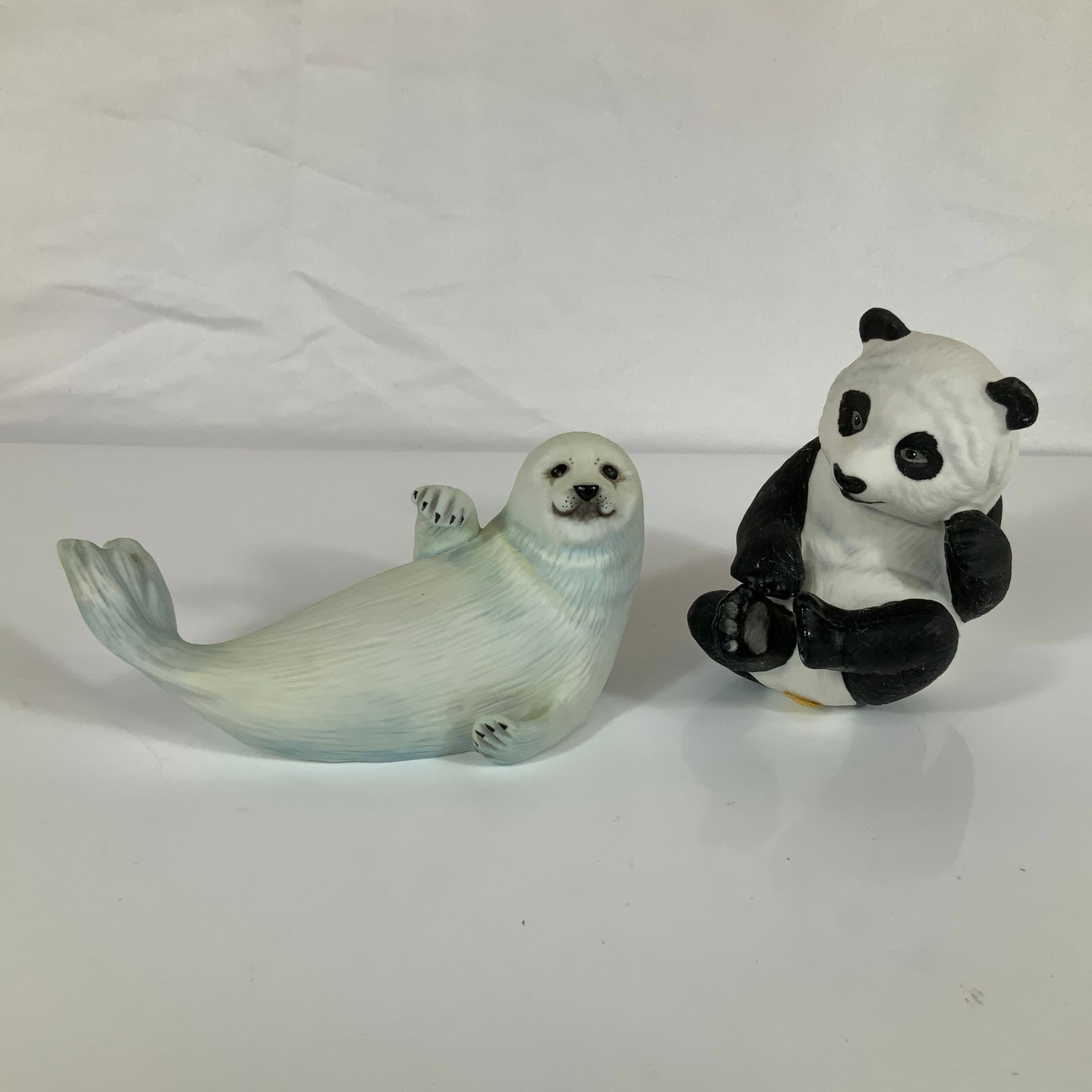 A Pair of Franklin Mint Porcelain Figurines Panda Pup and Snow Pup by Roslyn S Carren: This pair of hand-painted bisque porcelain figurines was produced by The Franklin Mint as an official issue for The Humane Society of the United States. Both pieces were designed by artist Roslyn S. C
