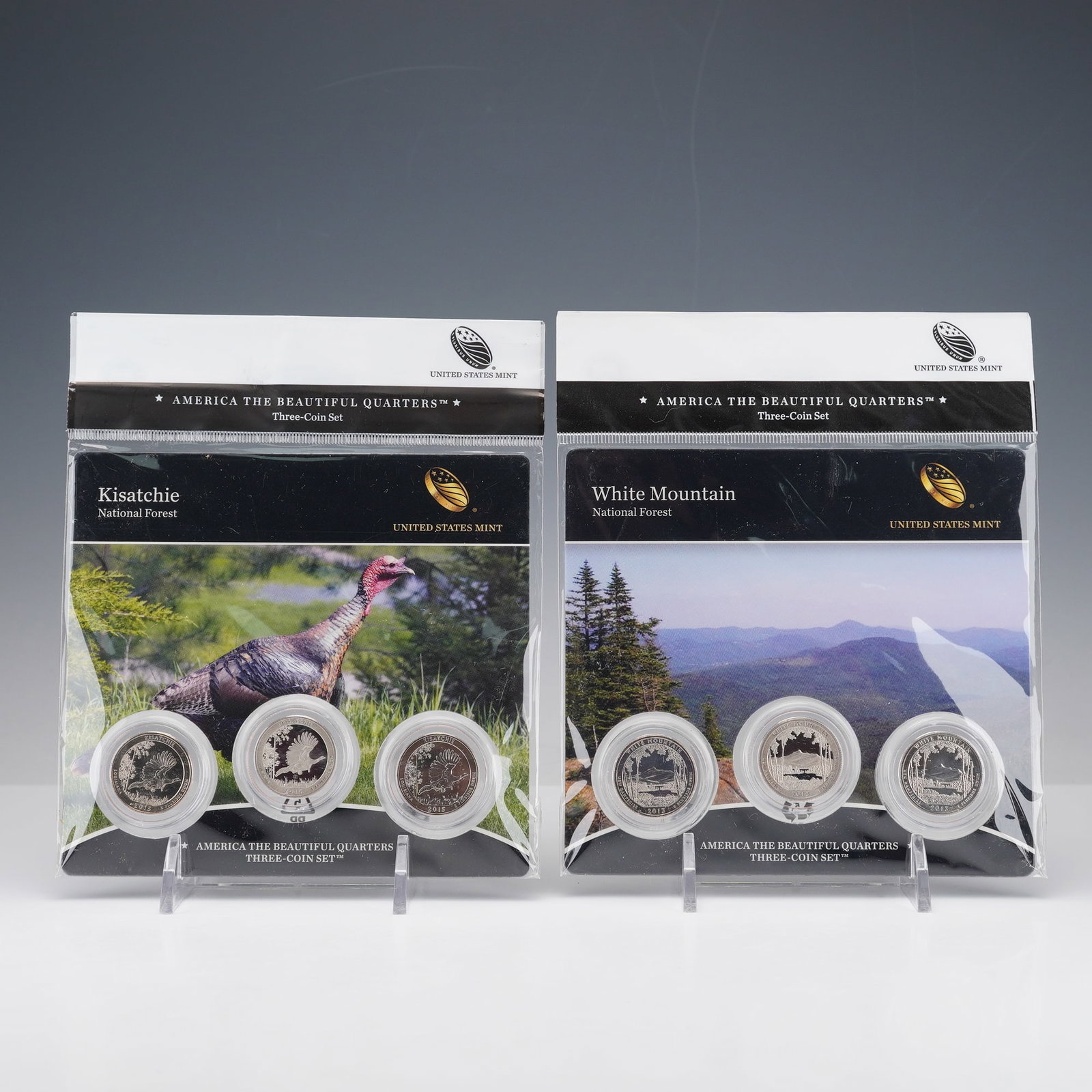 2pc 2013, 2015 America the Beautiful Three-Coin Quarters Sets: America the Beautiful Quarters three-coin sets, including White Mountain National Forest (2013) and Kisatchie National Forest (2015). Each set contains three versions of the same commemorative quarter