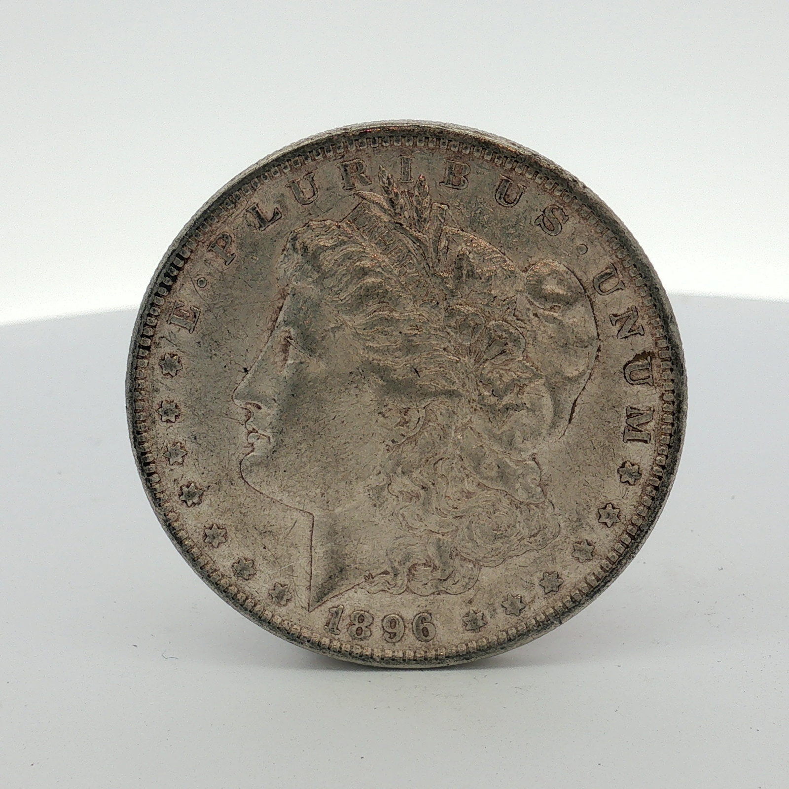 1896 US Morgan Silver Dollar Coin Circulated: This coin was struck at the Philadelphia Mint and is composed of 90% silver and 10% copper. It features the Liberty head obverse and the eagle reverse. The O mint mark is positioned on the reverse abo