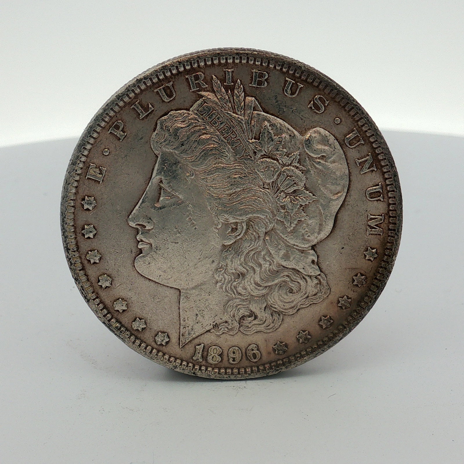 1896 US One Dollar Morgan Silver Dollar, Circulated: US 1896 Morgan silver dollar struck at the Philadelphia Mint. This coin is composed of 90 percent silver and 10 percent copper. It features a reeded edge and the standard Morgan design on the obverse 