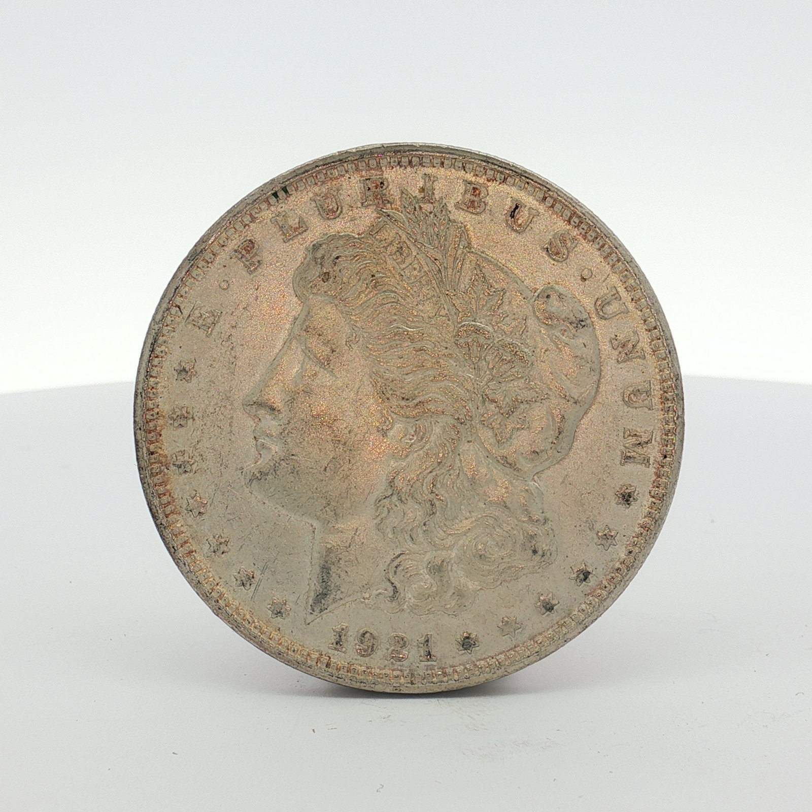 1921 US Morgan Silver Dollar Coin Circulated: This 1921 US Morgan silver dollar was struck at the Philadelphia mint. The coin is composed of 90 percent silver and 10 percent copper. It features the Morgan dollar Liberty Head obverse and Eagle wit