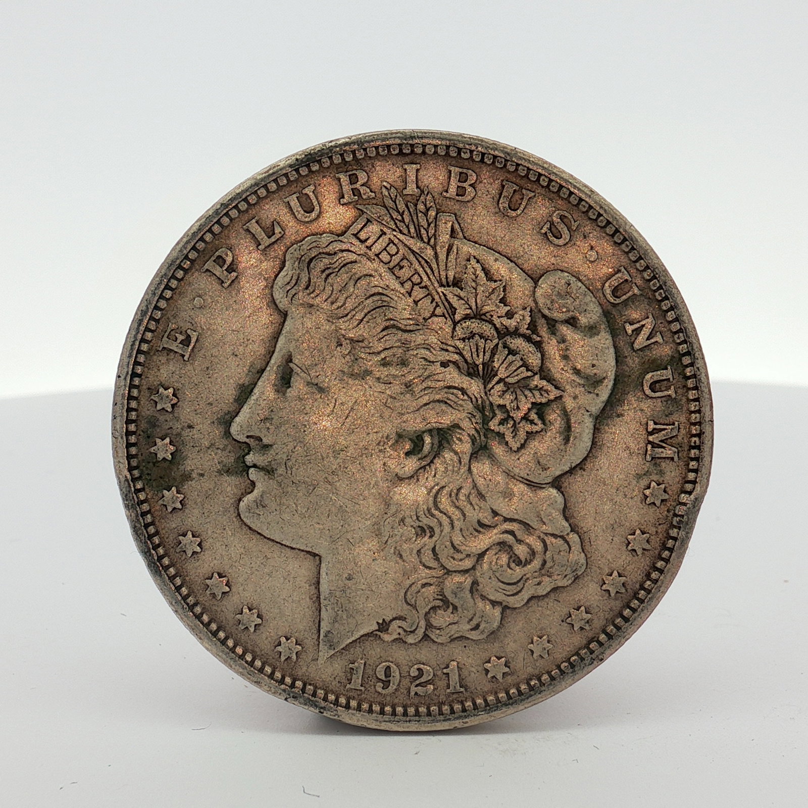 1921-S US Morgan Silver Dollar Coin Circulated: This US Morgan dollar was struck at the San Francisco Mint in 1921. The coin is composed of .900 fine silver and was produced using a die-struck method. The obverse features the Liberty head design, a