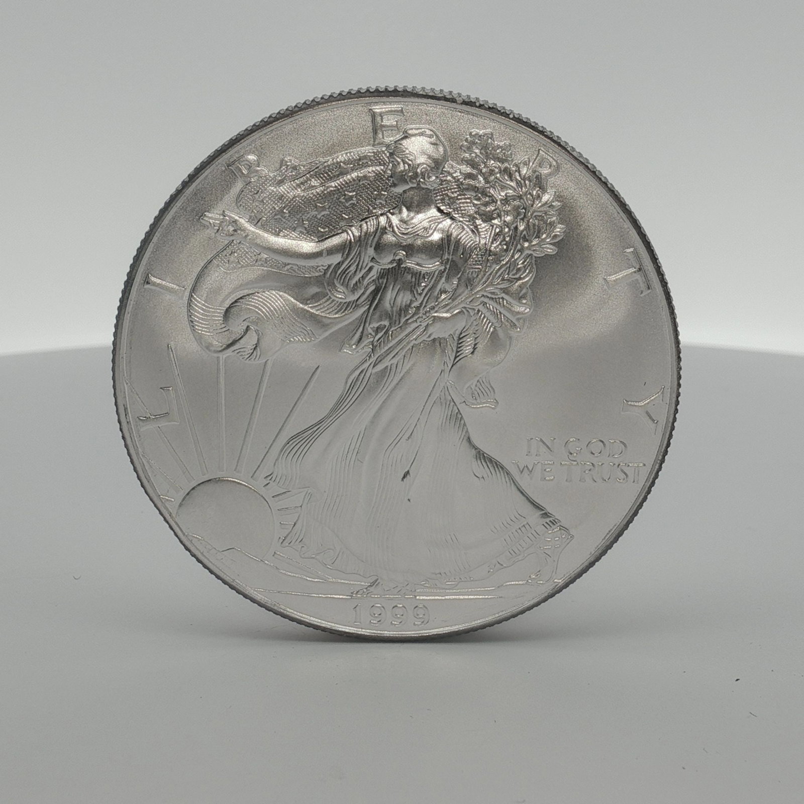 1999 American Silver Eagle One Dollar Coin: Minted by the Philadelphia Mint. The obverse side depicts an effigy of Walking Liberty with the date below. The reverse side depicts an heraldic eagle with shield United States of America and denomina