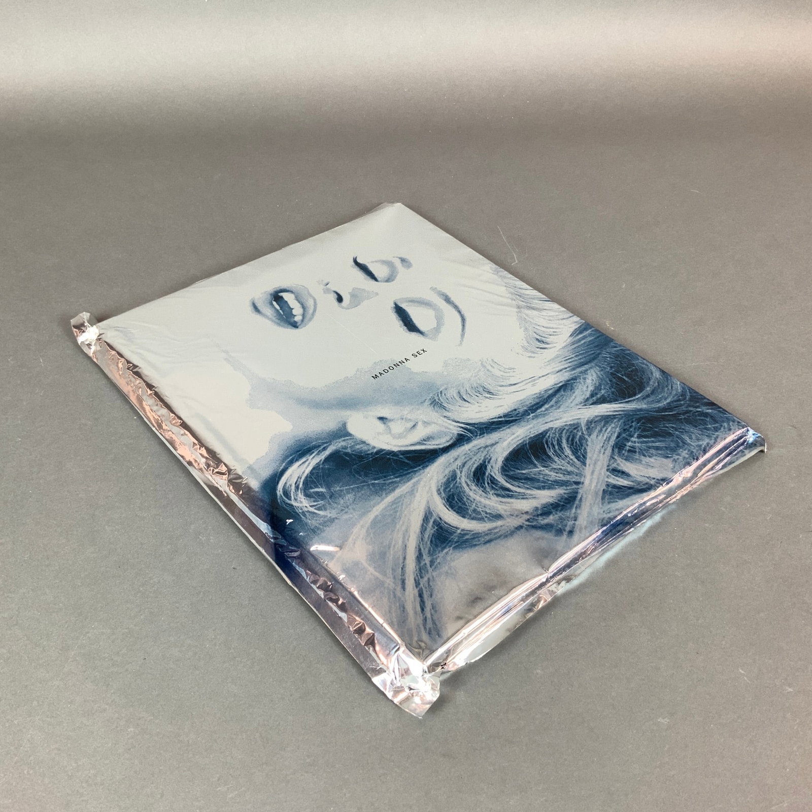 Madonna, Sex, Photography Book in Original Sealed Foil Wrapper, 1992: This is a copy of the photography book titled Sex by Madonna, published in 1992 by Warner Books. The item is presented in its original, characteristic silver metallic Mylar vacuum-sealed foil wrapper.