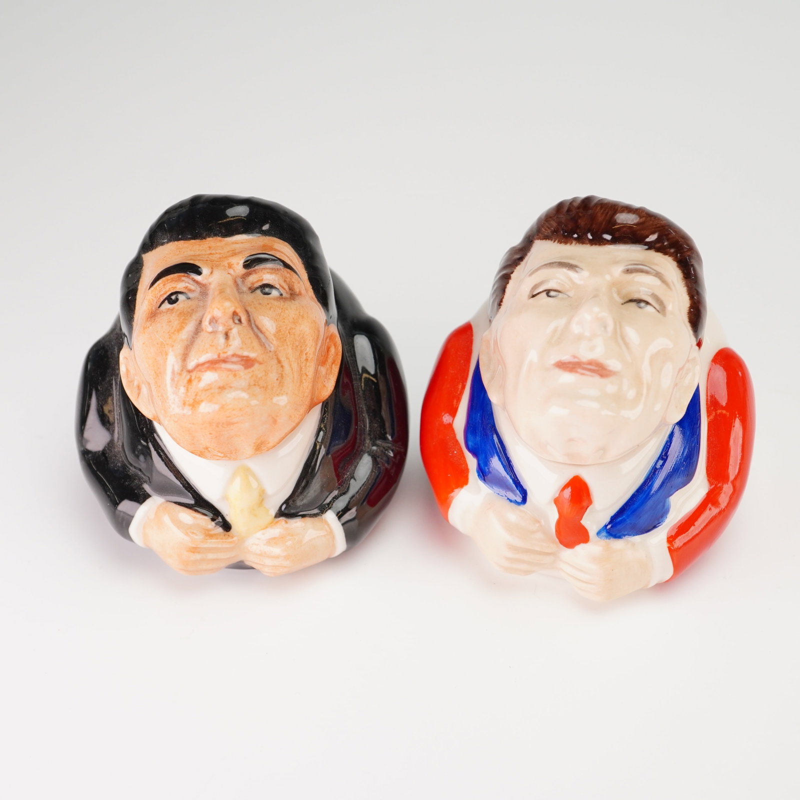 2pc Kevin Francis Face Pots, President Ronald Reagan: This lot features two hand-painted lidded ceramic miniature Face Pots produced by Kevin Francis, each modeled after United States President Ronald Reagan. The first pot depicts Reagan in a formal blac
