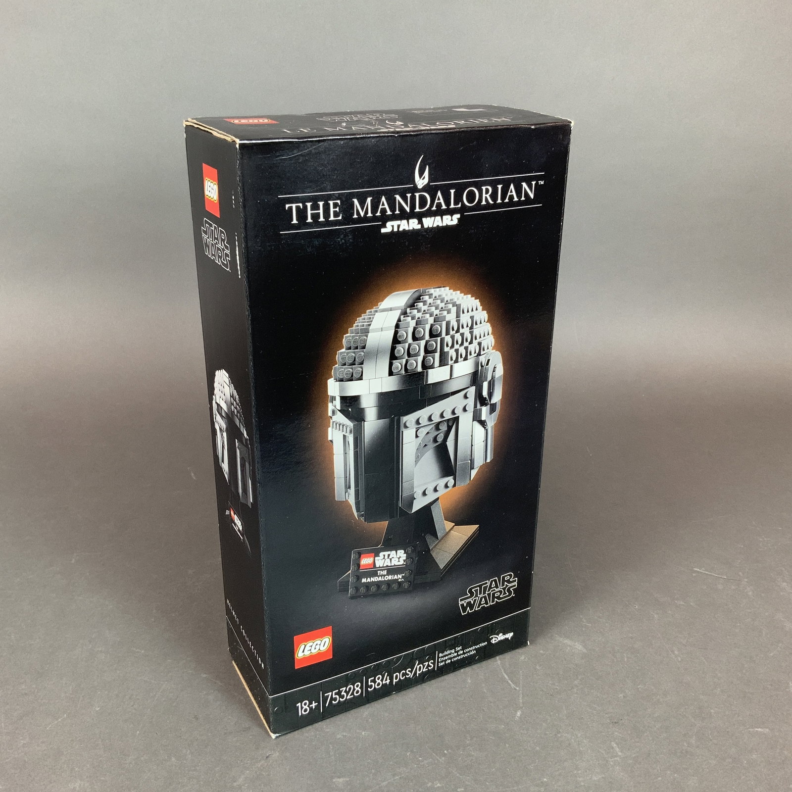 LEGO Star Wars Set, The Mandalorian 75328: This LEGO set from the Star Wars Helmet Collection depicts the helmet of the character from the series The Mandalorian. Identified as model number 75328, the construction kit consists of 584 plastic b