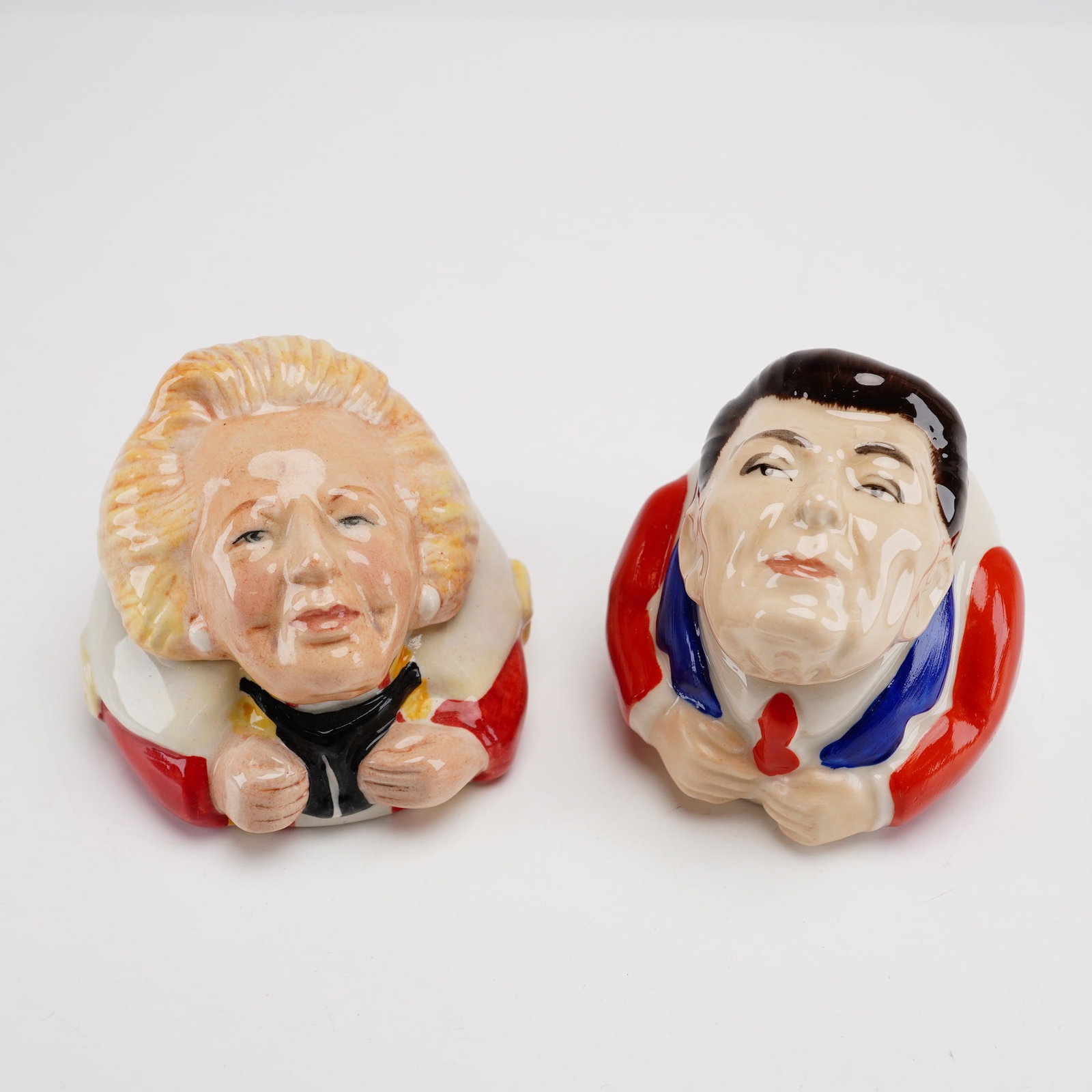 Lot of 2 Kevin Francis Face Pots Depicting Baroness Thatcher and President Reagan: A pair of Kevin Francis Face Pots featuring caricature depictions of Baroness Margaret Thatcher and President Ronald Reagan. These lidded ceramic figurines are rendered in a satirical, polychrome glaz