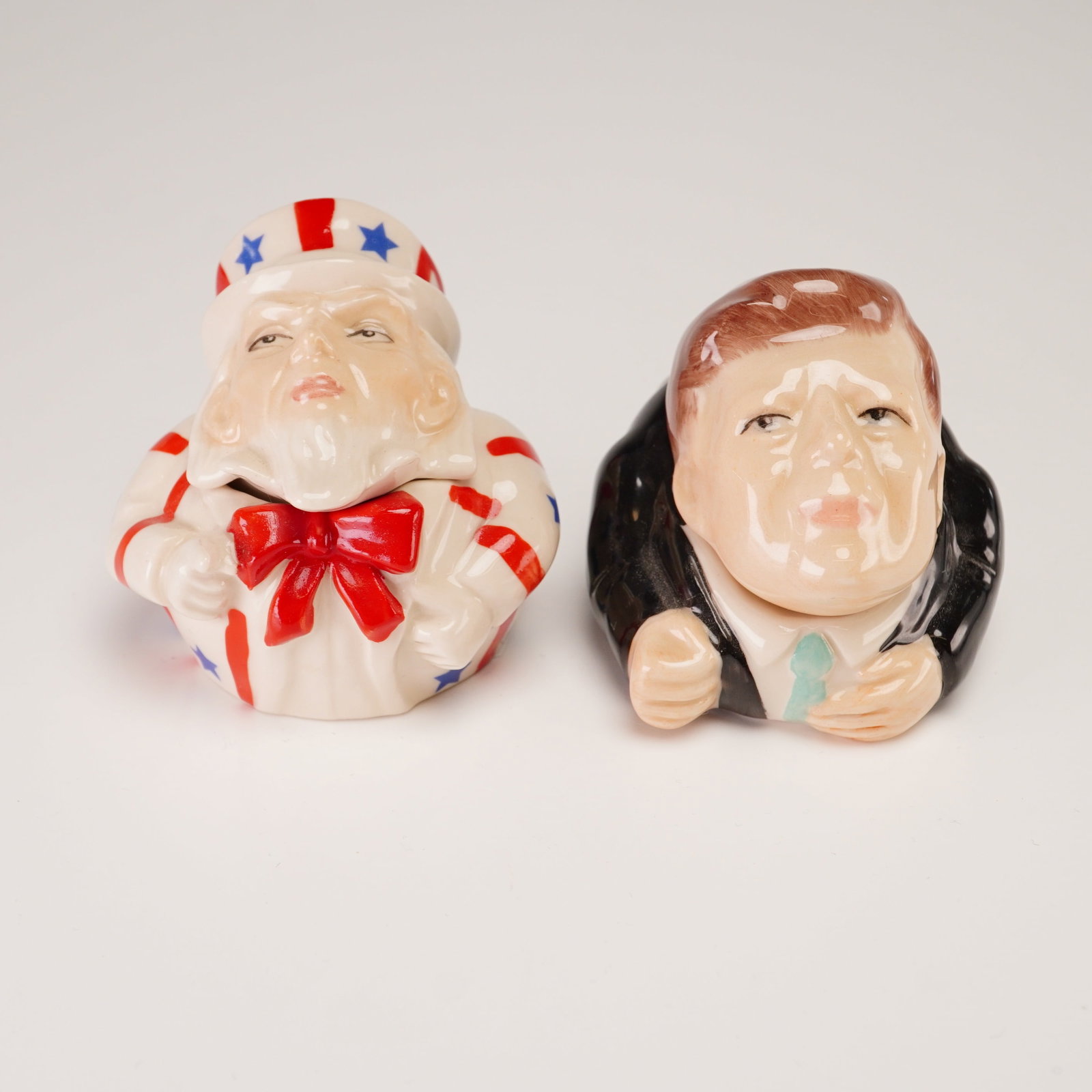 2pc Kevin Francis Face Pots, Prototype Uncle Sam and John F. Kennedy: A pair of Kevin Francis ceramic lidded containers from the Face Pots collection, featuring the likenesses of Uncle Sam and President John F. Kennedy. Each pot is comprised of a base and a removable li